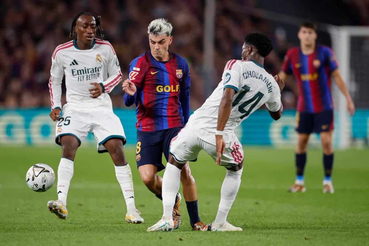 El centrocampista del FC Barcelona, Pedri (c), intenta superar al centrocampista francés del Real Madrid, Aurélien Tchouaméni, durante el encuentro de Laliga…