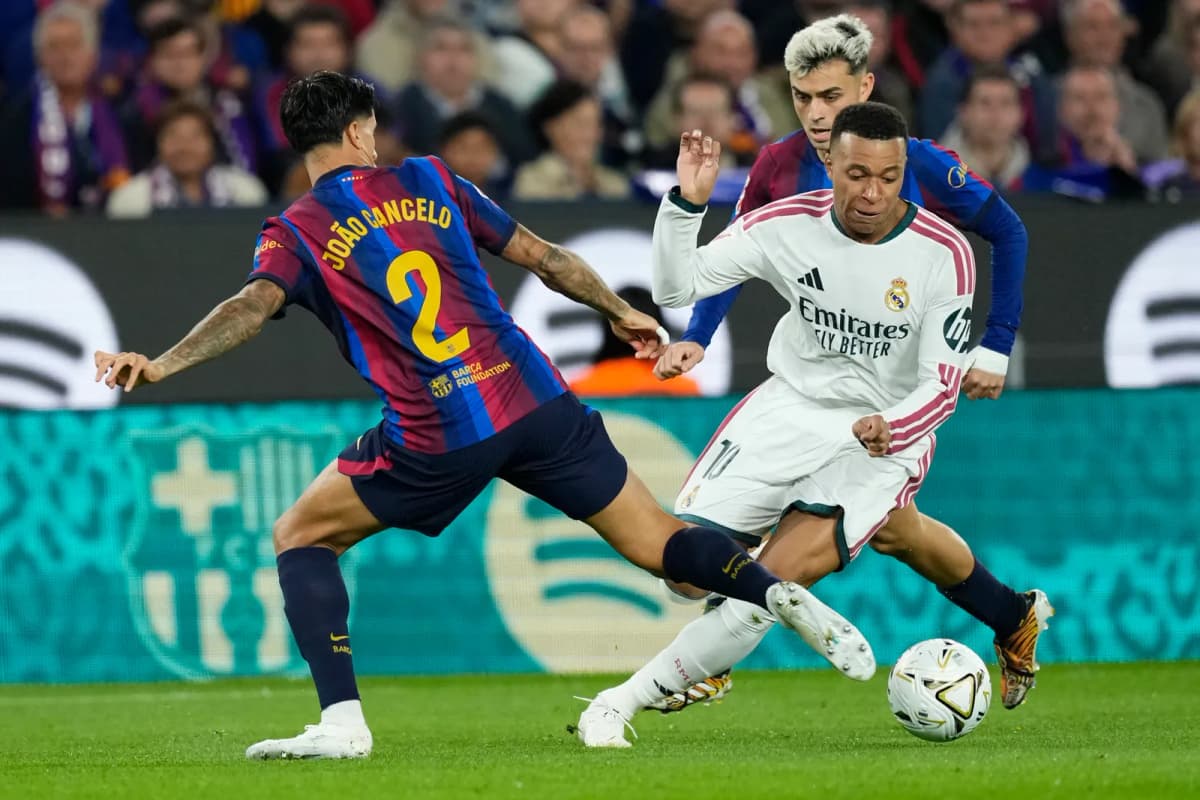 El delantero francés del Real Madrid, Kylian Mbappé (d), se lleva el balón ante los jugadores del FC Barcelona, el defensa portugués João Cancelo y el…