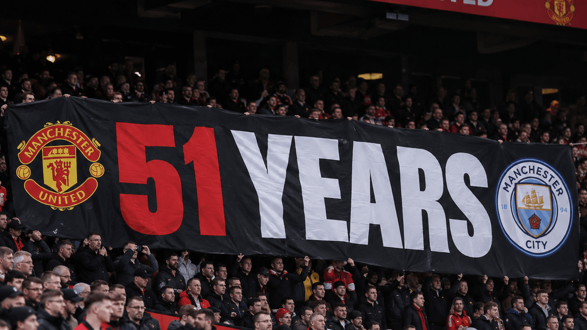 Vista de la grada Stretford End de Old Trafford, con una pancarta alusiva al Manchester City como posible portada.