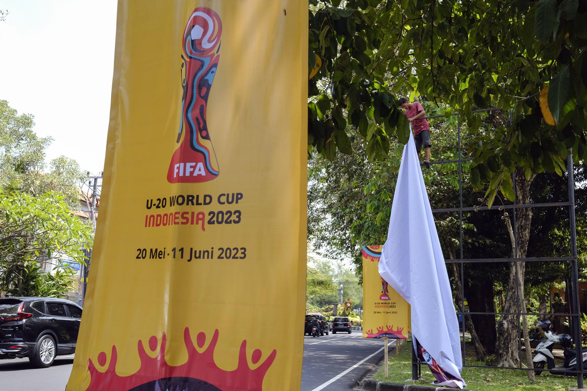 Un trabajador retira una pancarta de la Copa Mundial Sub-20 de la FIFA 2023 en un roan principal en Denpasar, Bali, Indonesia. EFE/EPA/MADE NAGI