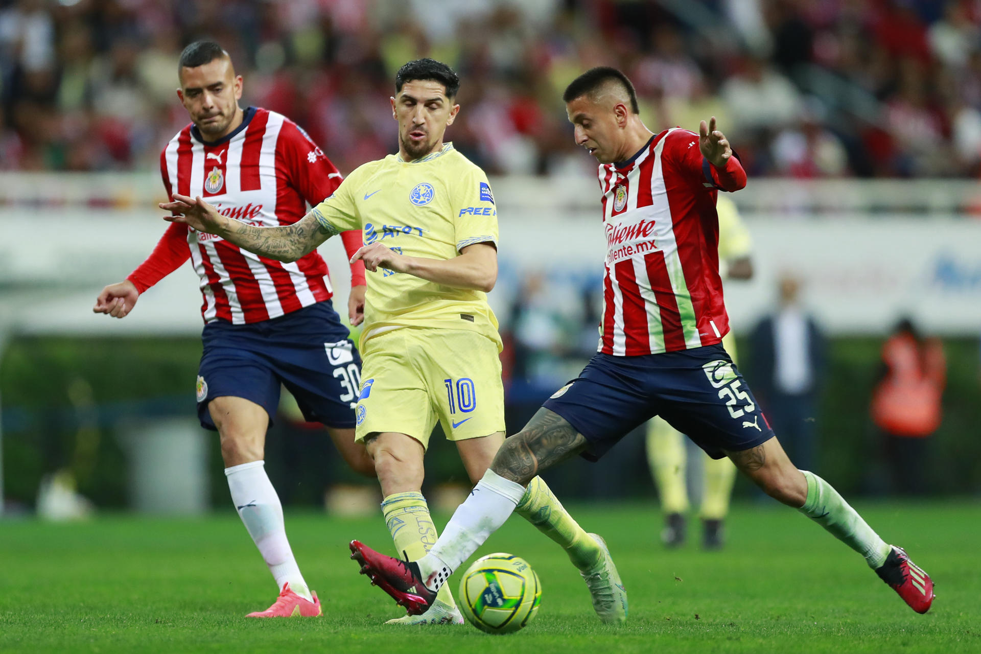 Roberto Alvarado (d) y Sergio Flores (i) del Guadalajara disputan el balón con Diego Valdés del América hoy, durante un partido de la jornada 12 del torneo clausura 2023 de la liga del fútbol mexicano. EFE/Francisco Guasco