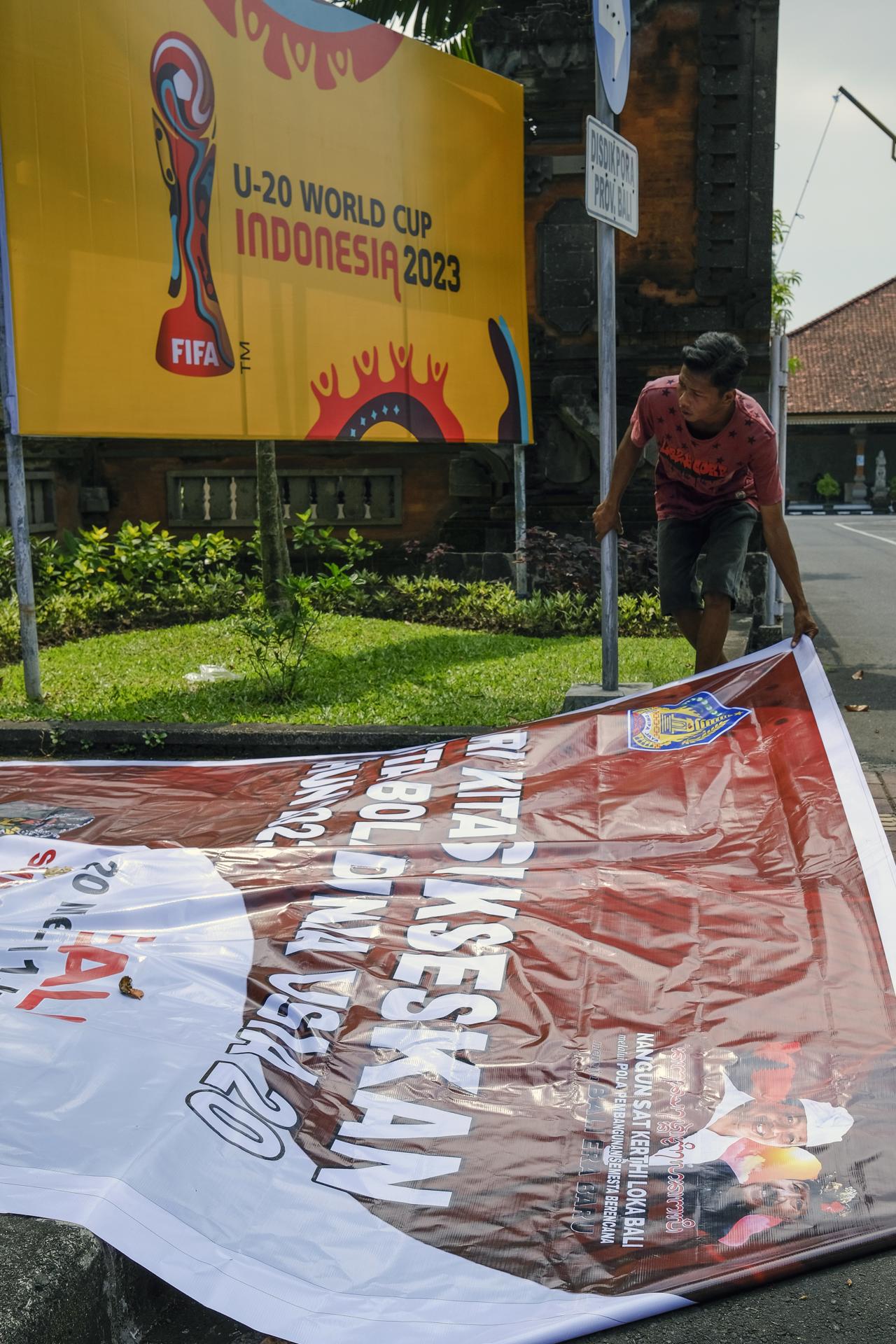 Un trabajador retira una pancarta de la Copa Mundial Sub-20 de la FIFA 2023 en un roan principal en Denpasar, Bali, Indonesia. EFE/EPA/MADE NAGI 