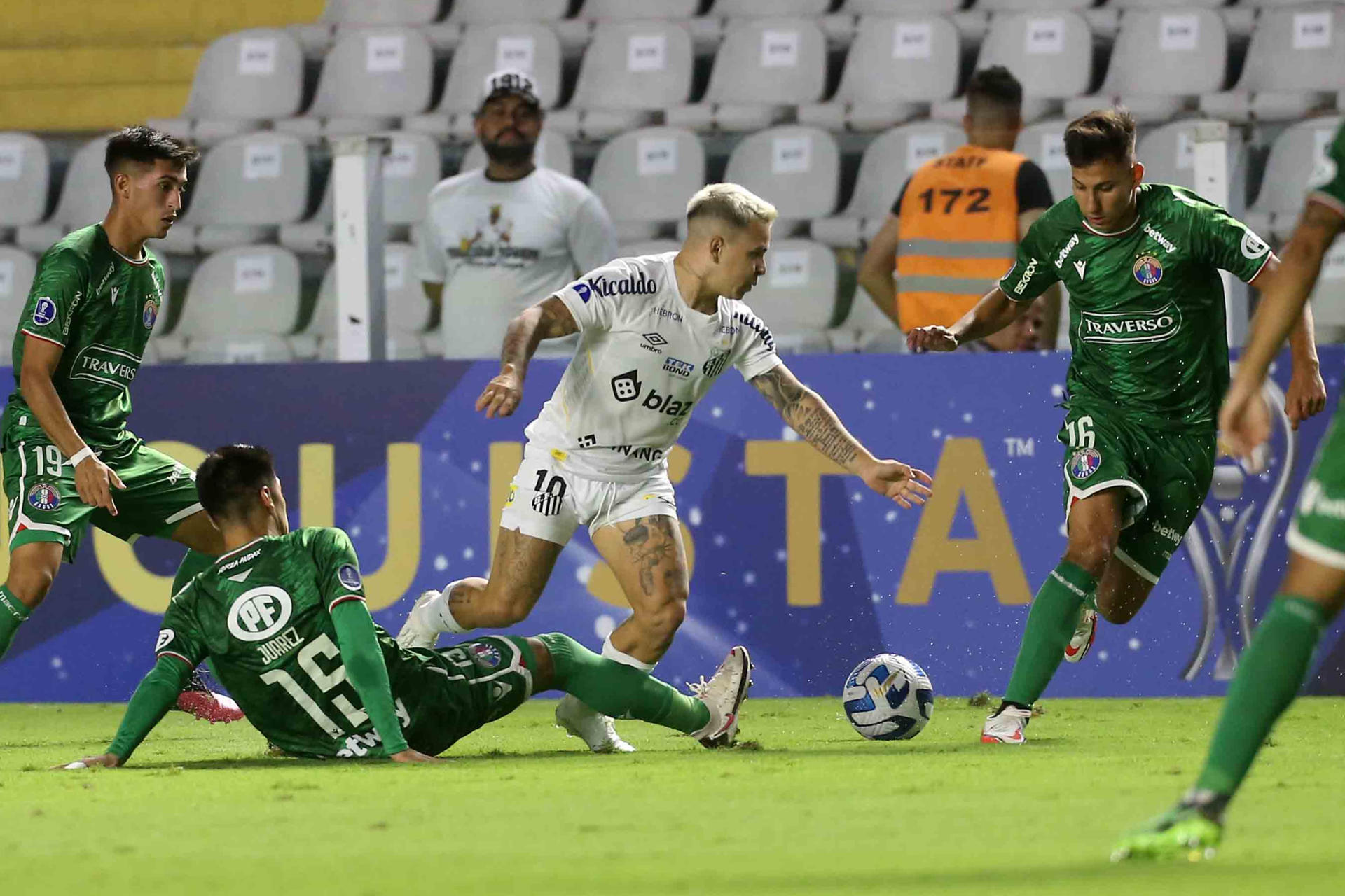 Yeferson Soteldo (c), del Santos de Brasil, fue registrado este jueves, 20 de abril, al disputar un balón con Fernando Juárez (abajo) y Óliver Rojas (d), del Audax Italiano de Chile, durante un partido del grupo E de la Copa Sudamericana, en el estadio Vila Belmiro, en Santos (Brasil). EFE/Guilherme Dionizio 