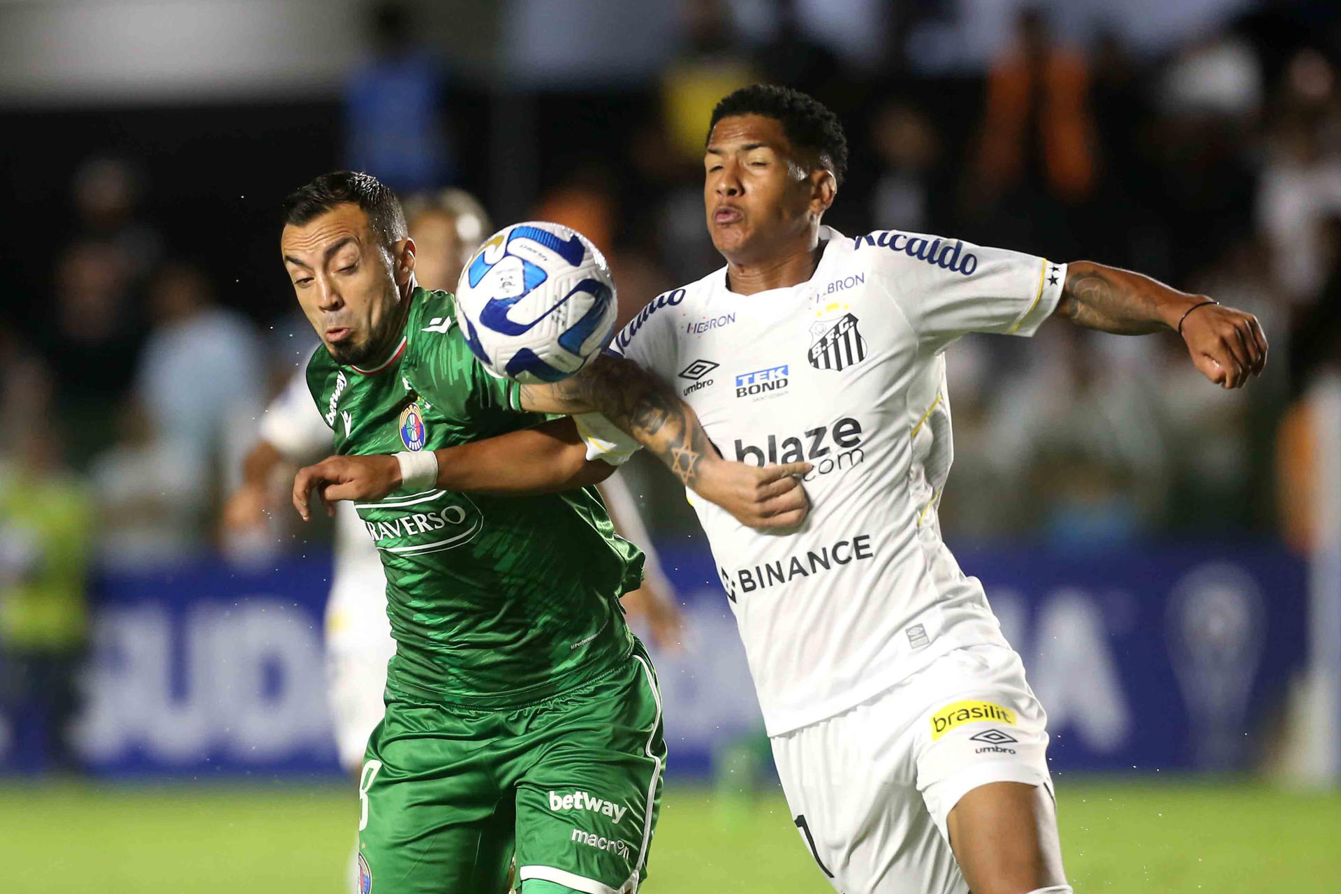 Angelo (d), del Santos de Brasil, fue registrado este jueves, 20 de abril, al disputar un balón con Roberto Cereceda, del Audax Italiano de Chile, durante un partido del grupo E de la Copa Sudamericana, en el estadio Vila Belmiro, en Santos (Brasil). EFE/Guilherme Dionizio