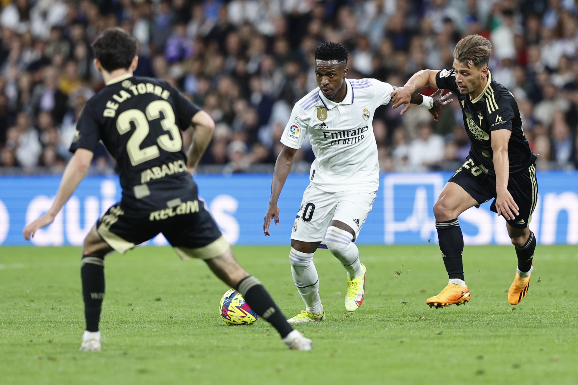 El delantero brasileño del Real Madrid, Vinicius Jr. (c), con el balón ante el defensa del Celta, Kevin Vázquez, durante el partido de la jornada 30 de Liga en el estadio Santiago Bernabéu, en Madrid. EFE/Rodrigo Jiménez