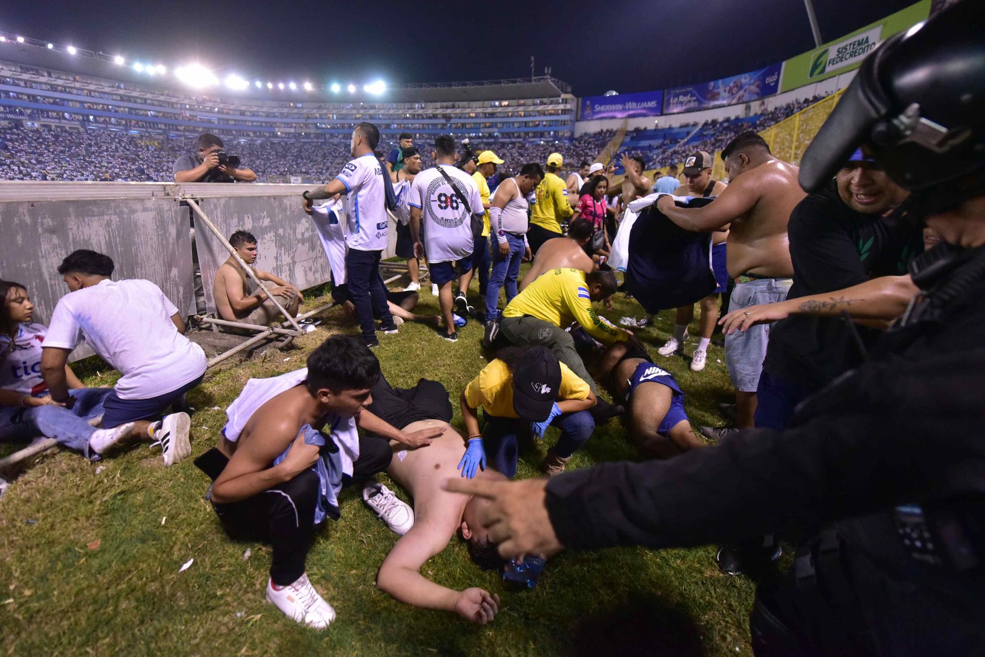 Fanáticos auxilian a personas durante una estampida en el Estadio Cuscatlán. EFE/ Miguel Lemus