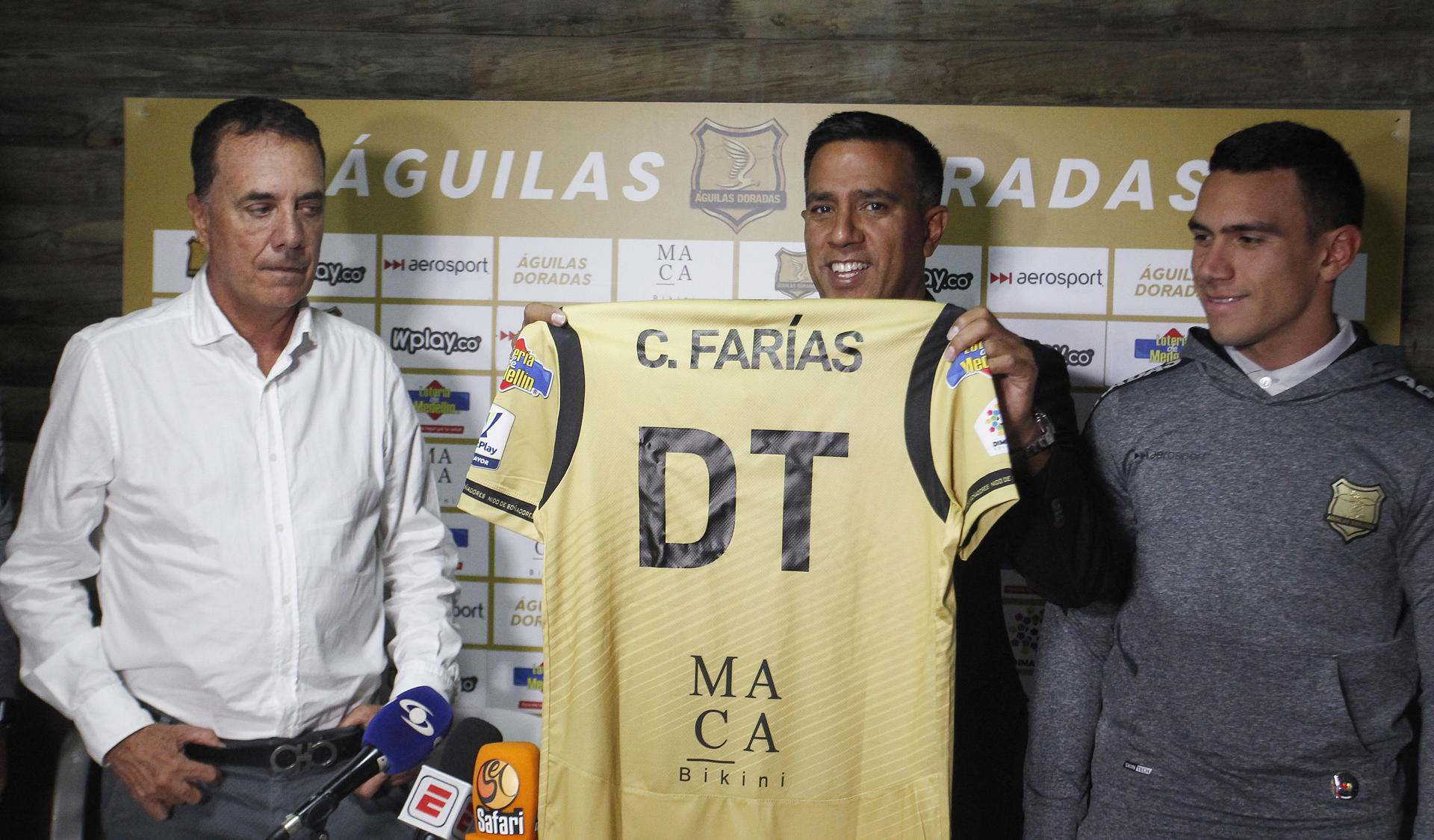 El entrenador venezolano César Farías (c) posa hoy, con una camiseta del equipo de fútbol Águilas Doradas junto a Jesús Ramírez (i), integrante de la junta directiva del equipo y su asistente técnico e hijo Jesús Farías (d), durante la rueda de prensa de presentación como nuevo director técnico del equipo colombiano Águilas Doradas, en Rionegro, Antioquia (Colombia). EFE/Luis Eduardo Noriega A.