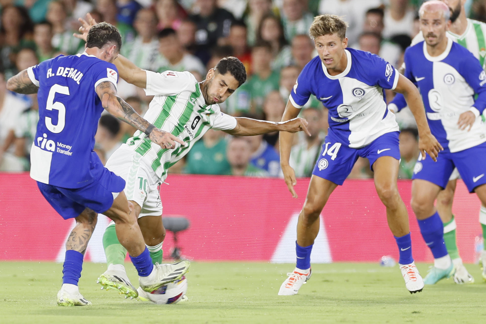 El centrocampista del Betis Ayoze Pérez (2i) lucha con el argentino Rodrigo de Paul (i), del Atlético de Madrid, durante el partido de la segunda jornada de LaLiga que disputan este domingo el Real Betis y el Atlético de Madrid en el estadio Benito Villamarín, en Sevilla. EFE/José Manuel Vidal 