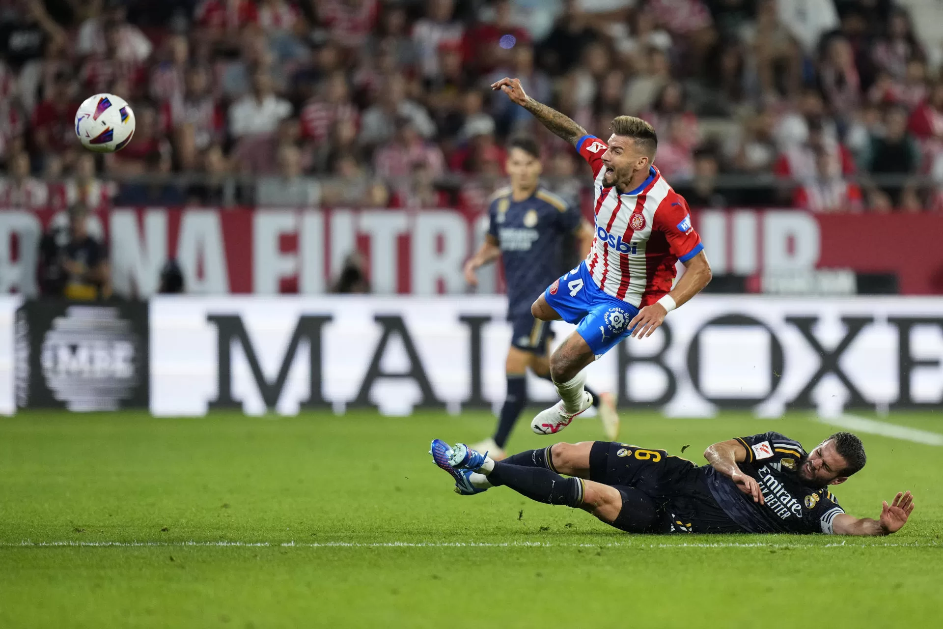 El centrocampista del Girona Cristian Portugués "Portu" (encima) pelea un balón con el defensa del Real Madrid Nacho Fernández durante el partido de la jornada 8 de Liga de Primera división entre el Girona y el Real Madrid. EFE/Siu Wu