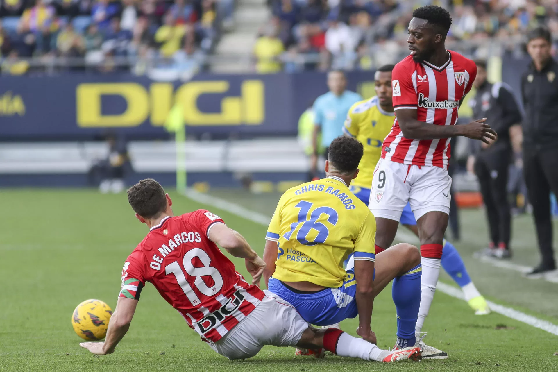El delantero del Cádiz CF, Chris Ramos (c) lucha por el balón con el delantero del Athletic Club de Bilbao, Iñaki Williams y el defensa del Athletic Club de Bilbao De Marcos (i) este domingo, durante el partido de LaLiga EA Sports, entre el Cádiz CF y el Athletic Club de Bilbao, en el estadio Nuevo Mirandillade Cádiz. EFE/ Román Ríos