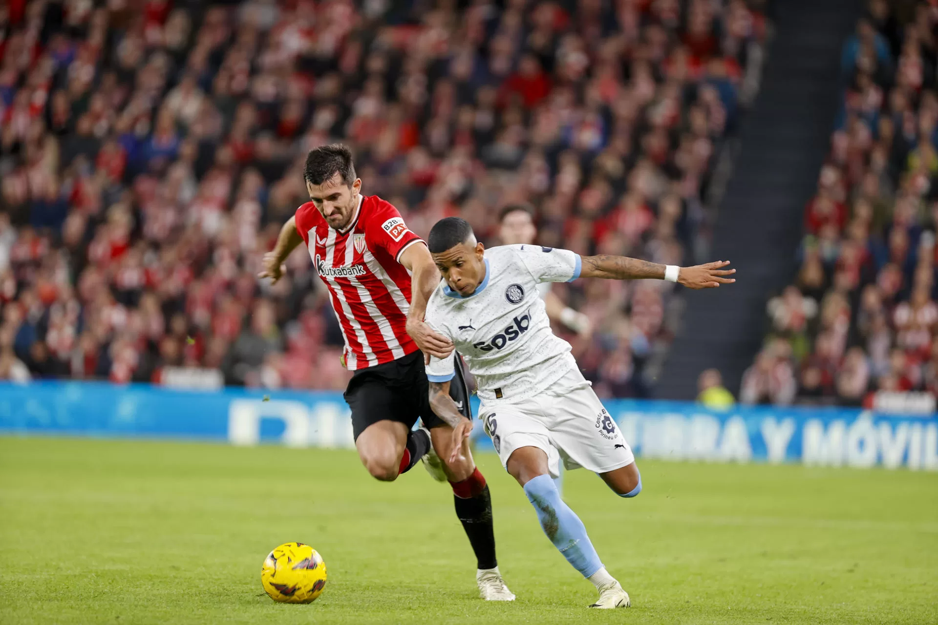 El defensa del Athletic Club Vivian (i) disputa una posesión con el delantero brasileño del Girona Sávio durante el encuentro correspondiente a la jornada 25 de LaLiga EA Sports disputado entre Athletic Club y Girona FC en San Mamés, Bilbao. EFE/ Luis Tejido 