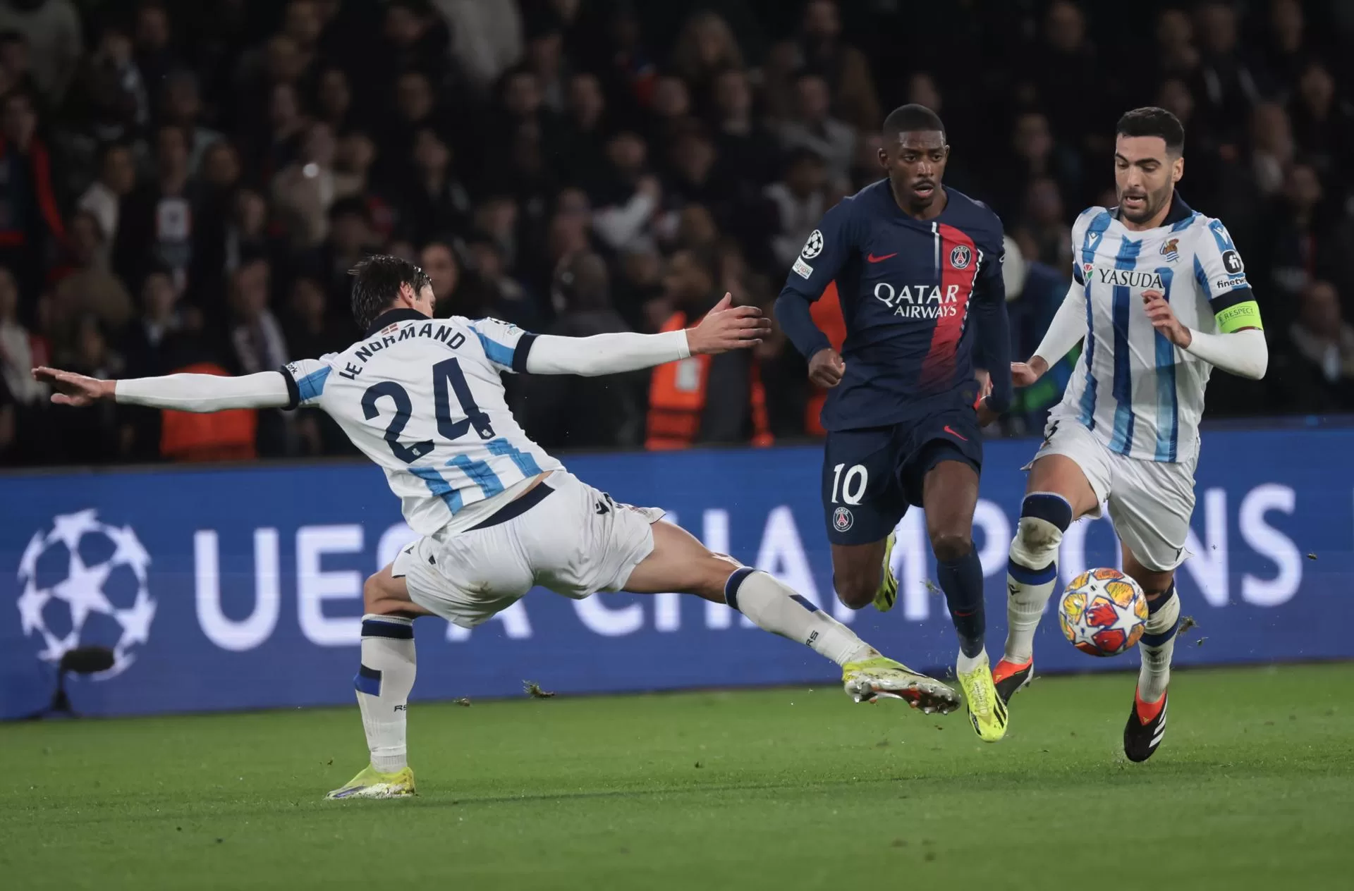 El jugador del Paris Saint Germain Ousmane Dembele (c) y Mikel Merino de la Real Sociedad en ación durante el partido de octavos de la Liga de Campeones qujugado en el Parque de los Príncipes de París. EFE/EPA/CHRISTOPHE PETIT TESSON 