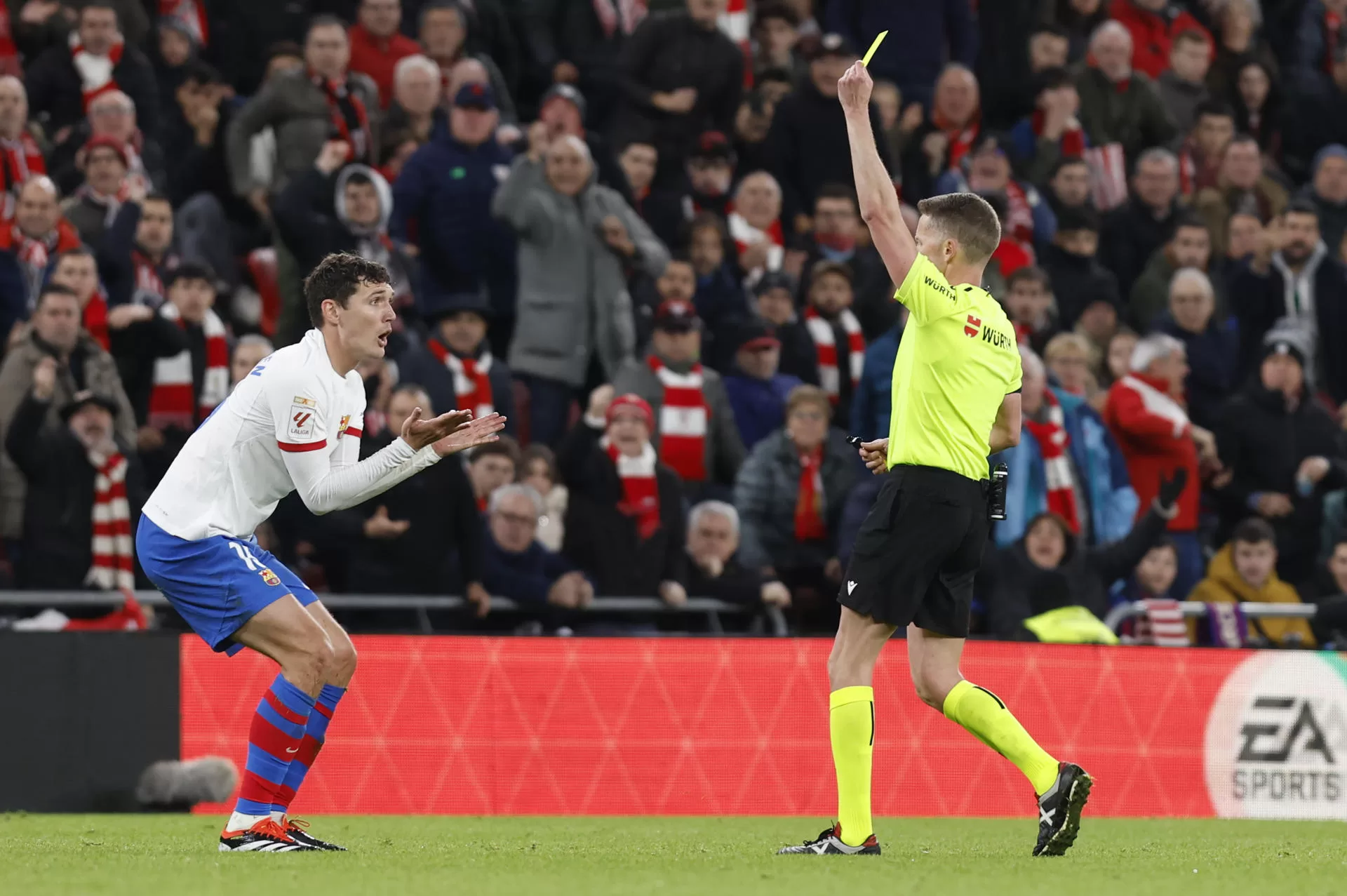 El árbitro Hernández Hernández (d) muestra tarjeta amarilla al centrocampista danés del FC Barcelona Andreas Christensen (i) durante el partido de Liga de Primera División que el Athletic Club y el FC Barcelona disputaron en el estadio de San Mamés. EFE/Miguel Toña
