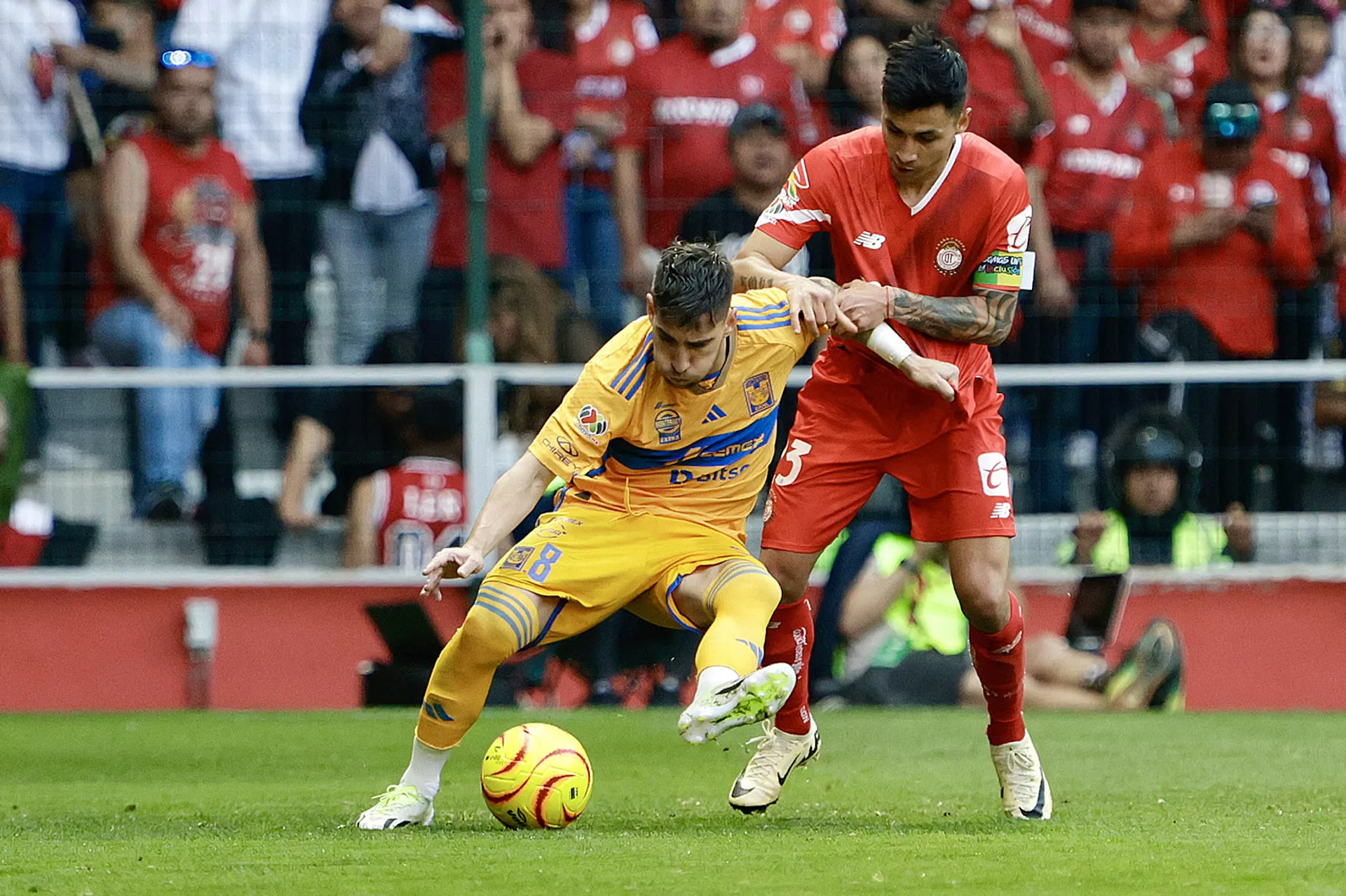 Fernando Gorriarán (i) de Tigres disputa un balón con Claudio Baeza de Toluca este sábado. EFE/Alex Cruz 