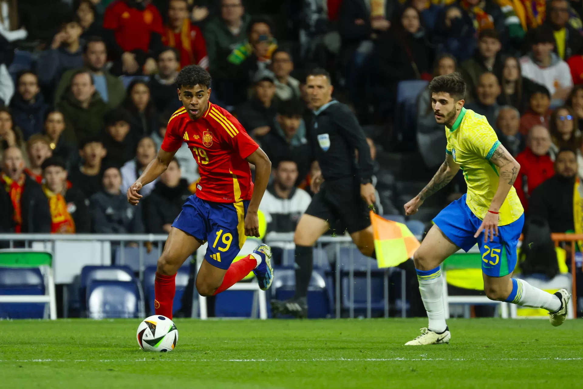 El delantero de la selección española Lamine Yamal (i) disputa un balón frente a Lucas Beraldo, defensa de la selección brasileña, durante el partido amistoso que las selecciones nacionales de fútbol de España y Brasil disputaron en el estadio Santiago Bernabéu, en Madrid. EFE/Mariscal