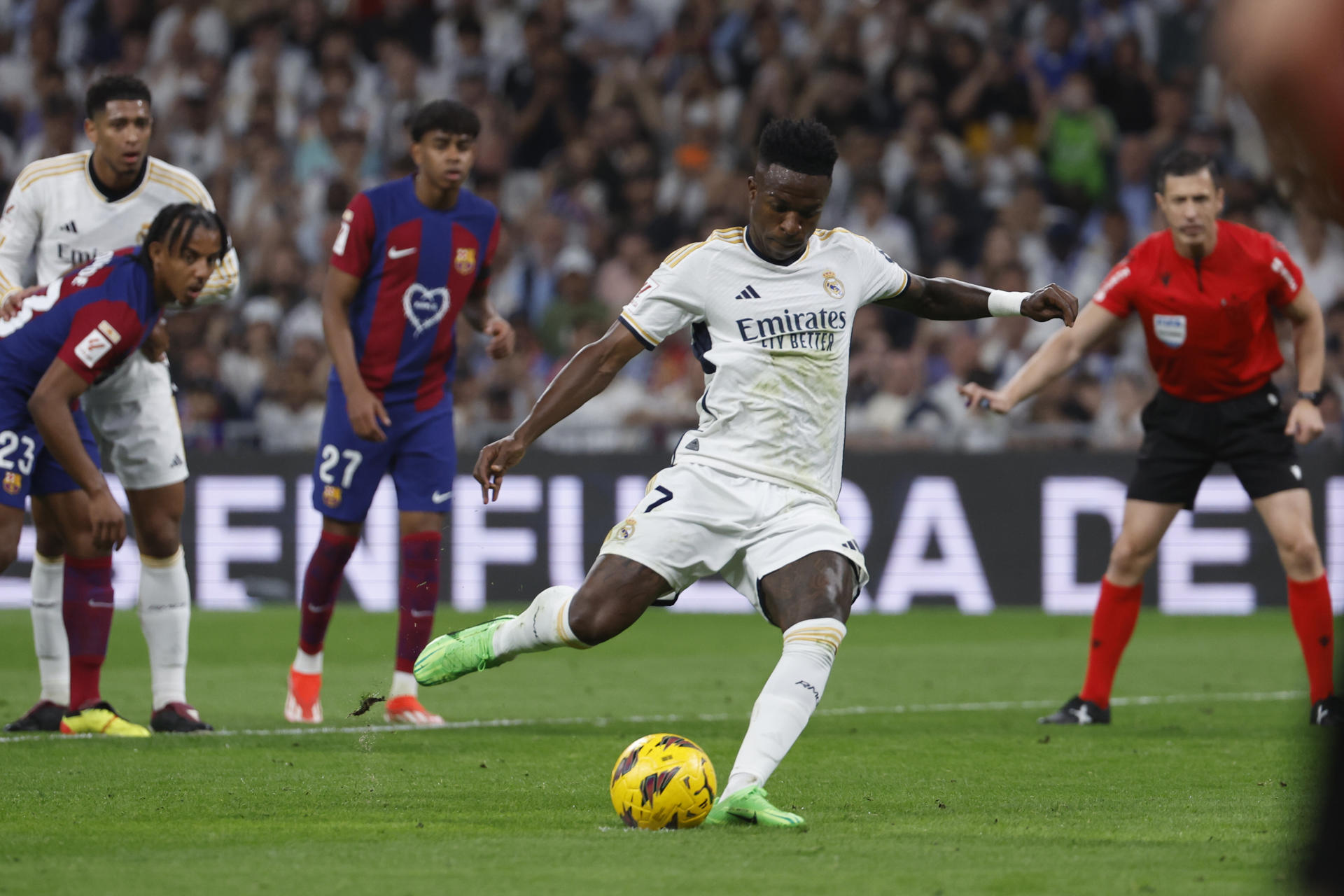 El delantero brasileño del Real Madrid Vinícius Jr (c) marca el 1-1 de penalti durante el partido de la jornada 32 de LaLiga EA Sports entre Real Madrid y FC Barcelona, en el estadio Santiago Bernabéu de Madrid. EFE/ Daniel González