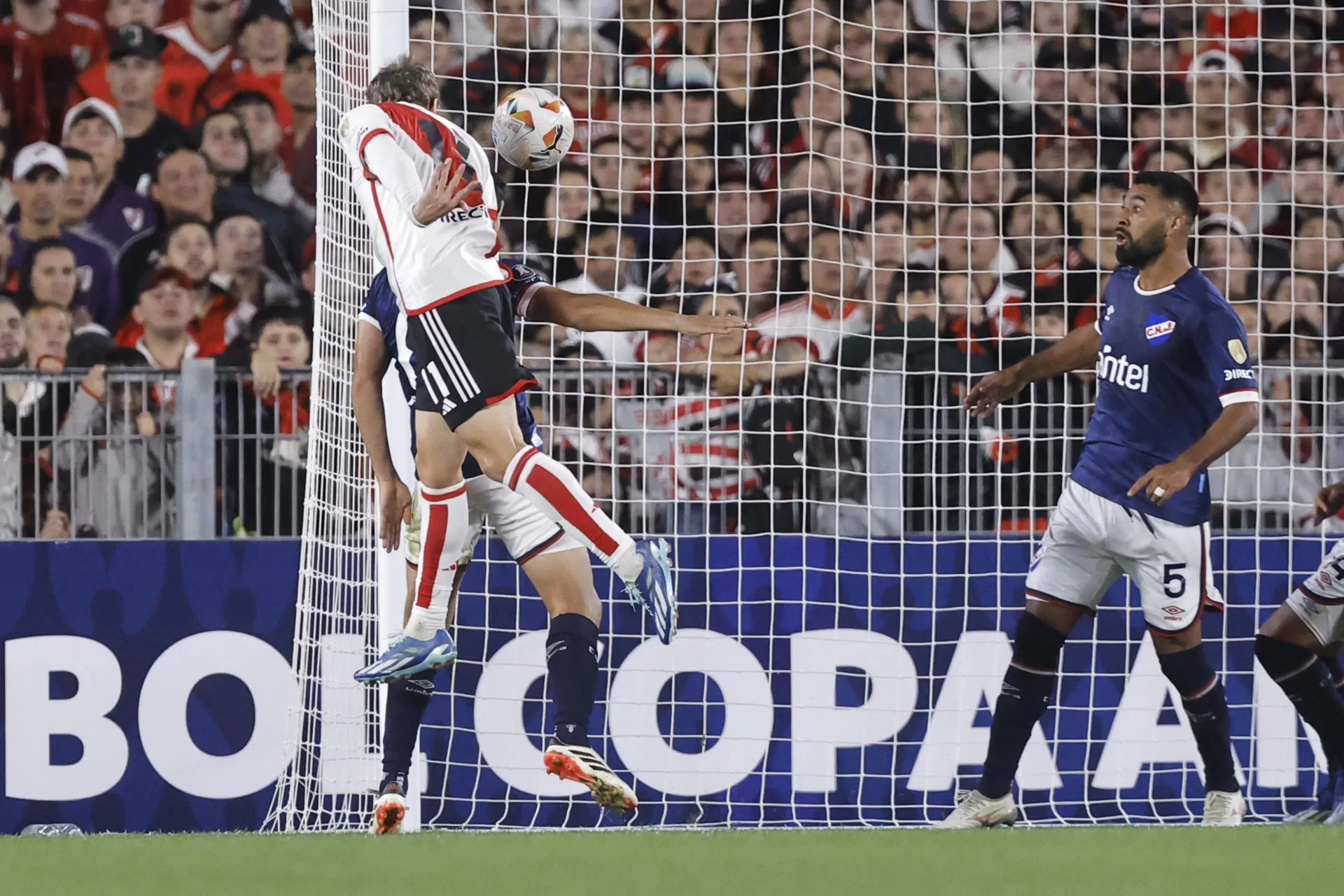 Facundo Colidio (i) conecta de cabeza el segundo gol con el que River Plate derrotó este jueves por 2-0 a Nacional de Montevideo en un partido de la segunda jornada de la fase de grupos de la Copa Libertadores jugado en el estadio Más Monumental en Buenos Aires. EFE/ Juan Ignacio Roncoroni 