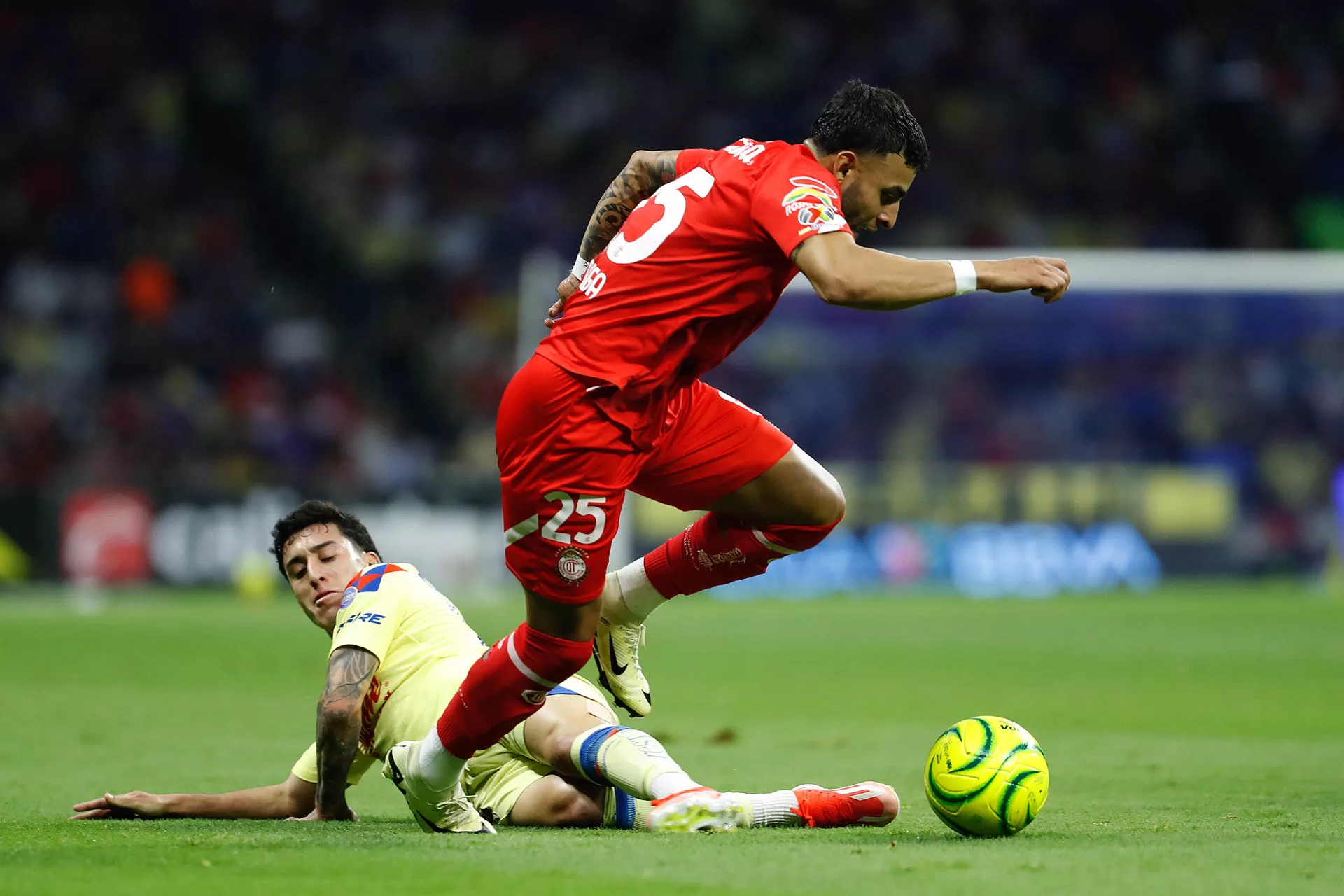 Alejandro Zendejas (i), de América, disputa el balón con Ernesto Vega (d), de Toluca, este sábado durante un partido de la decimoquinta jornada del torneo Clausura mexicano jugado en el estadio Azteca de Ciudad de México. EFE/ Sáshenka Gutiérrez