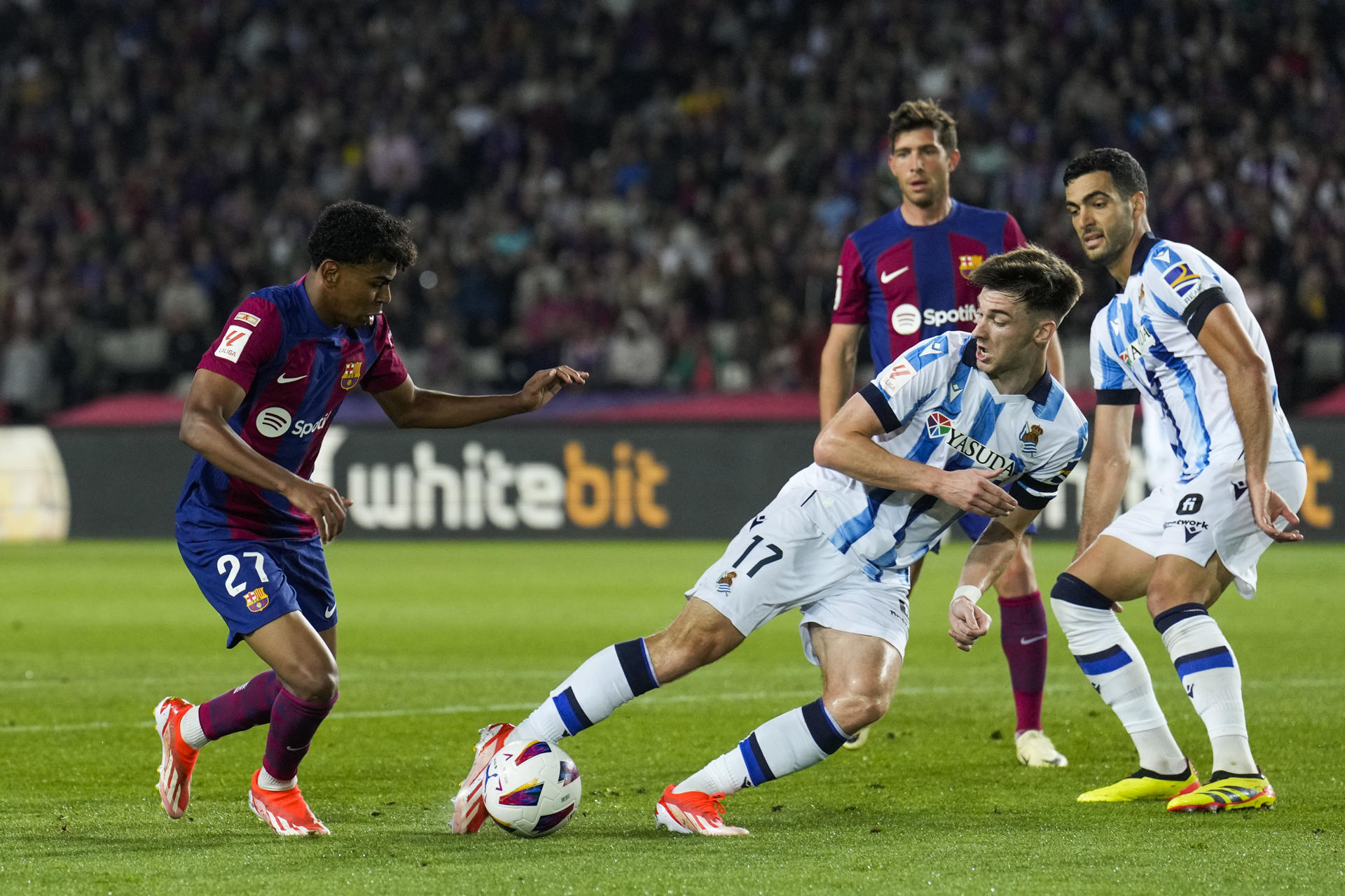 El delantero del FC Barcelona Lamine Yamal (i) lucha con el escocés Kieran Tierney, de la Real Sociedad, durante el encuentro correspondiente a la jornada 35 en Primera División que FC Barcelona y Real Sociedad disputan hoy lunes en el estadio Olímpico Lluis Companys, en Barcelona. EFE/Alejandro García