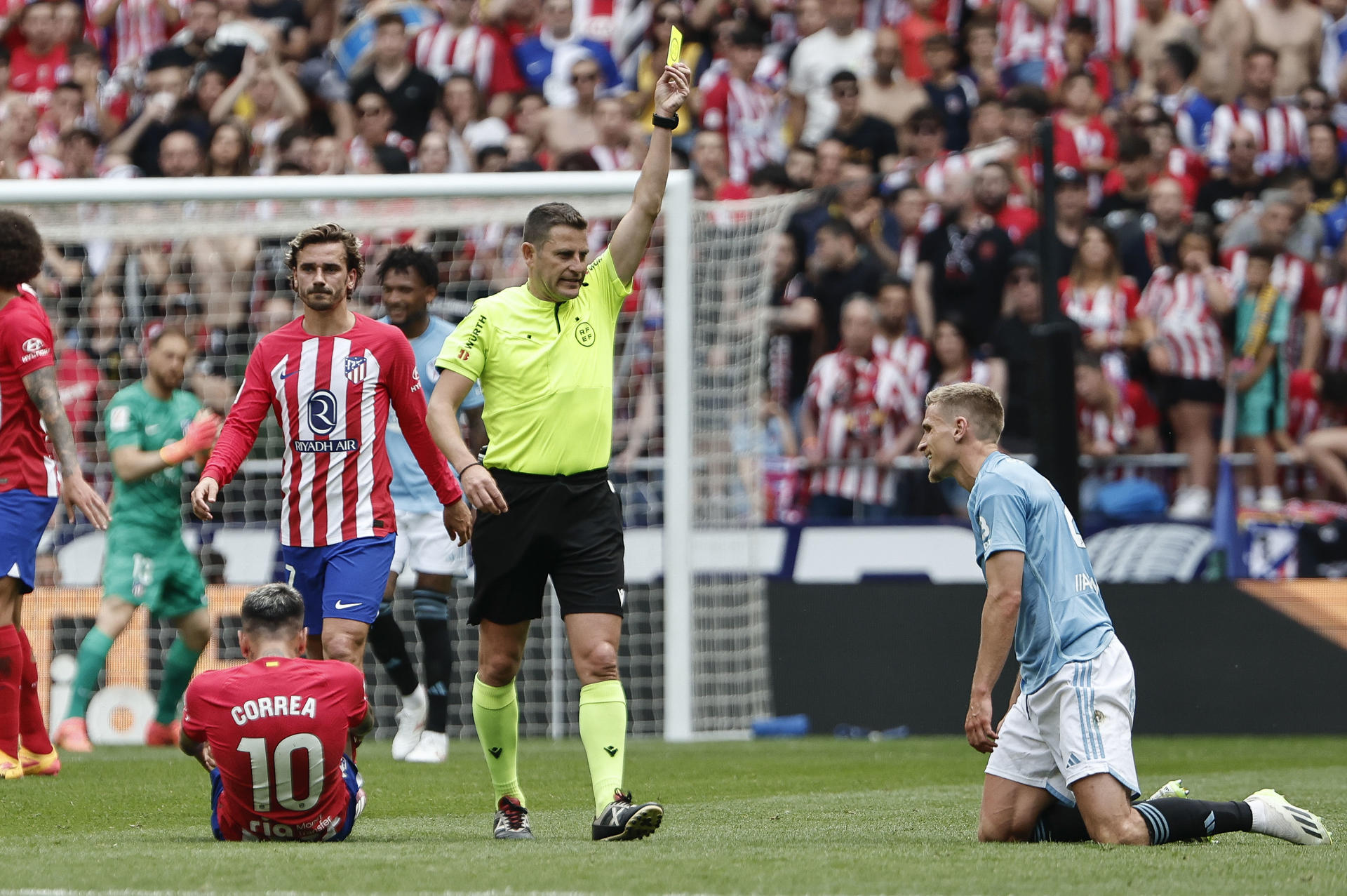 El delantero argentino del Atlético de Madrid, Ángel Correa, en el suelo tras sifrir una entrada del defensa sueco del Celta Carl Starfelt, que recibe tarjeta amarilla, durante el partido de LaLiga entre el Atlético de Madrid y el Celta, este domingo en el estadio Metropolitano. EFE/ Sergio Pérez 