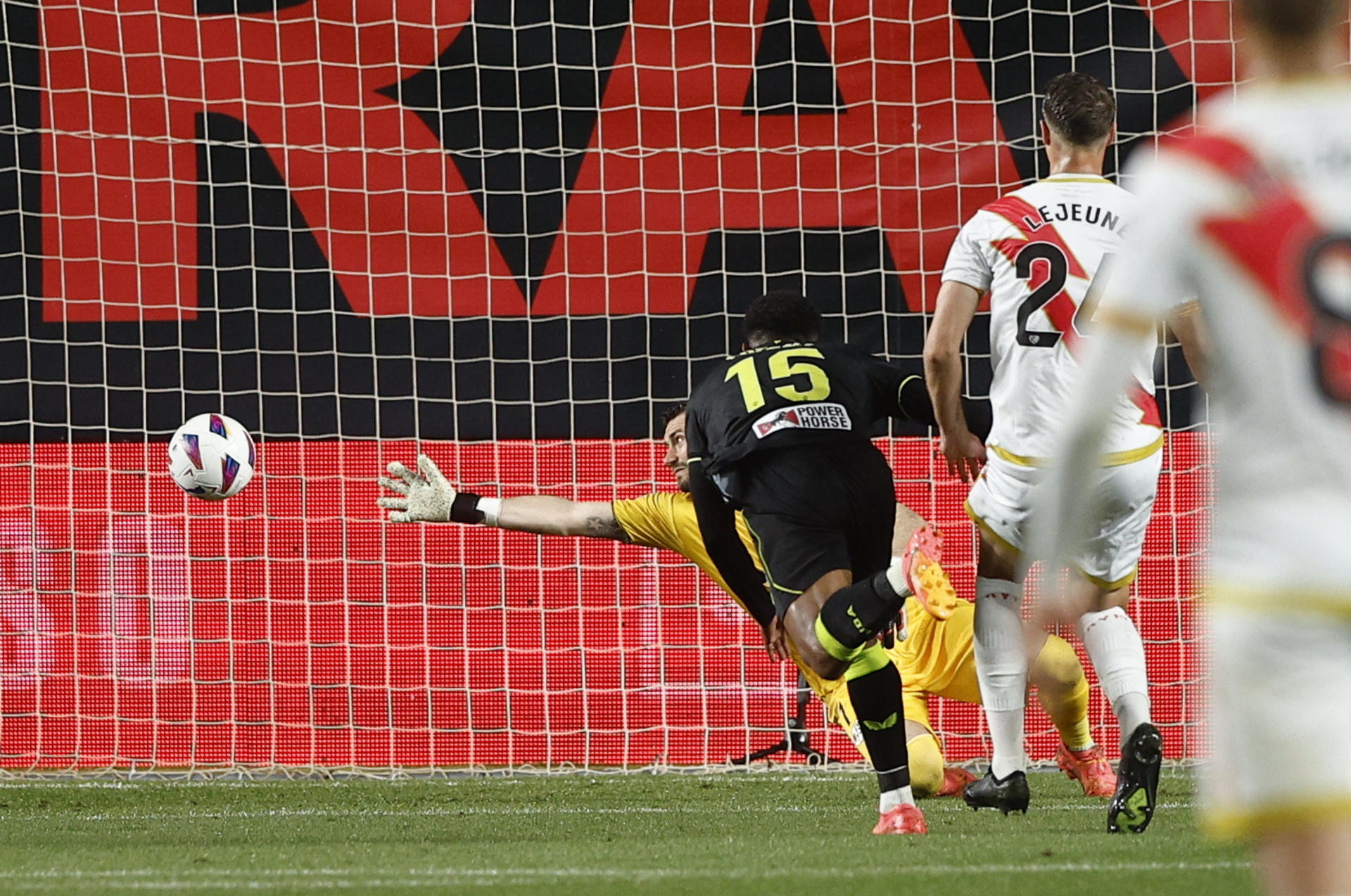 El delantero hondureño del Almería, Lozano, remata ante el guardameta macedonio del Rayo Vallecano, Stole Dimitrievski, para conseguir el primer gol de su equipo durante el encuentro correspondiente a la jornada 34 de Primera División en el estadio de Vallecas, en Madrid. EFE / Rodrigo Jiménez. 