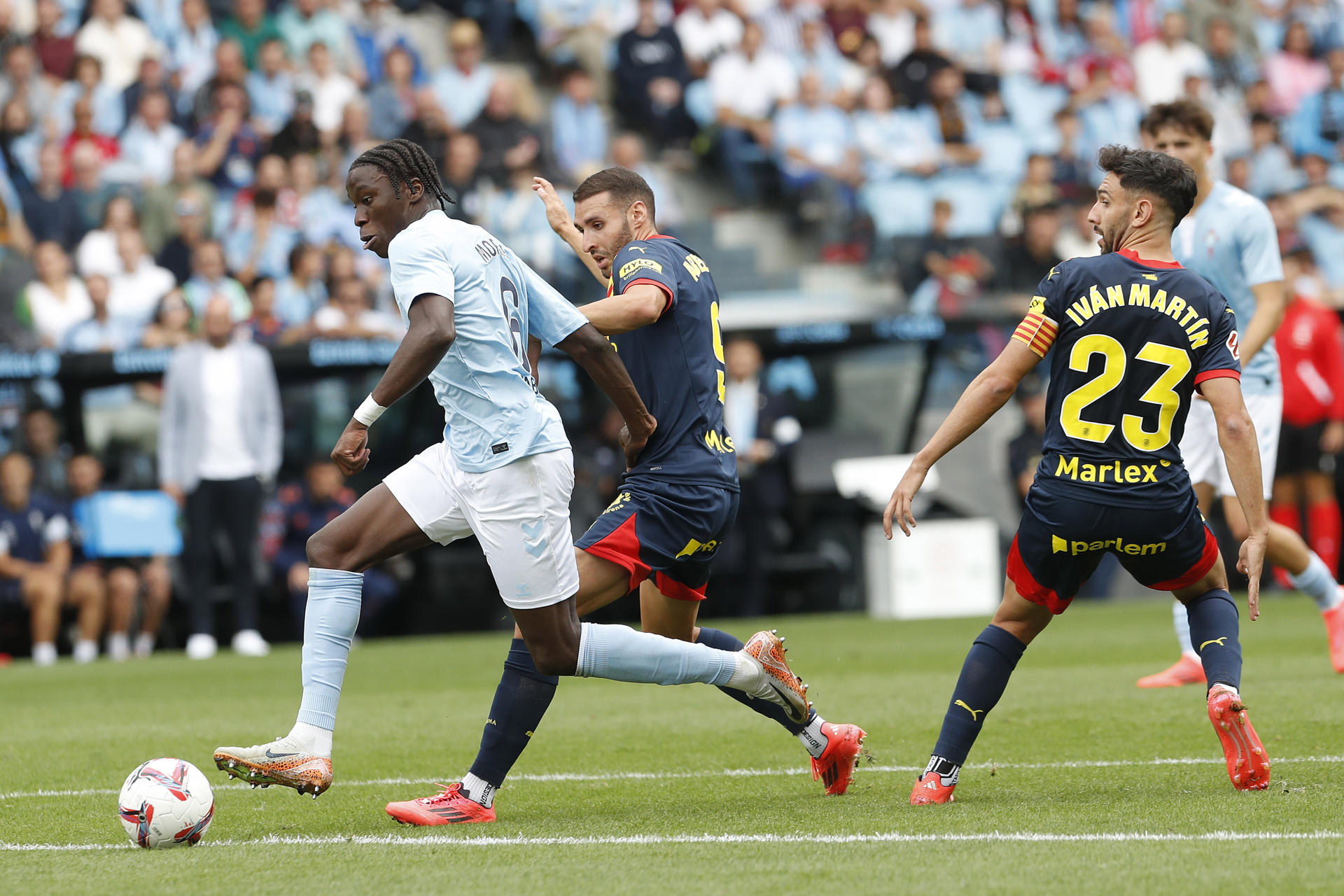 El delantero del Girona Abel Ruiz (c) presiona al centrocampista guineano Ilaix Moriba (i) del Celta de Vigo durante el partido de LaLiga entre el Celta de Vigo y el Girona celebrado este domingo el estadio Balaidos de Vigo. EFE / Salvador Sas 