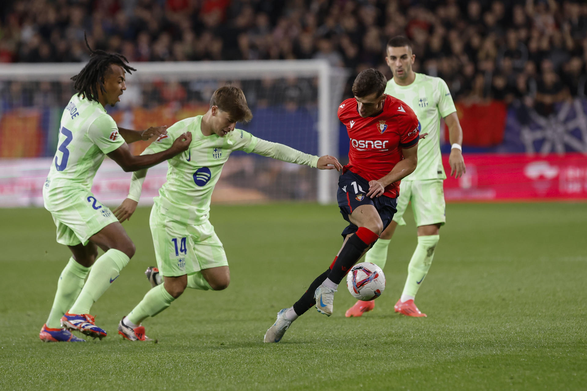 El centrocampista de Osasuna Aimar Oroz (2-d) trata de escapar de Pablo Torre (2-i) y Jules Koundé (i), del Barcelona, durante el partido de LaLiga en Primera División en el estadio de El Sadar, en Pamplona. EFE/Villar López
