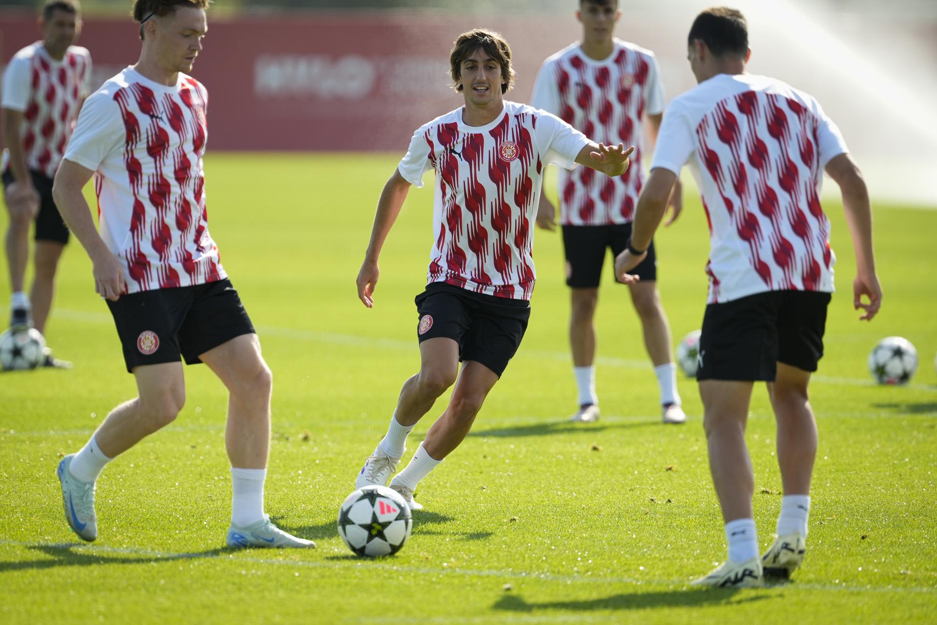 Los jugadores del Girona FC, Viktor Tsygankov (i) Bryan Gil (c), durante el entrenamiento que realiza la plantilla rojiblanca en las instalaciones del Girona Football Academy by PUMA para preparar el partido de Liga de Campeones que disputarán ante el París Saint-Germain en el Parque de los Príncipes, uno de los partidos de la primera jornada de la fase liga.EFE/ David Borrat