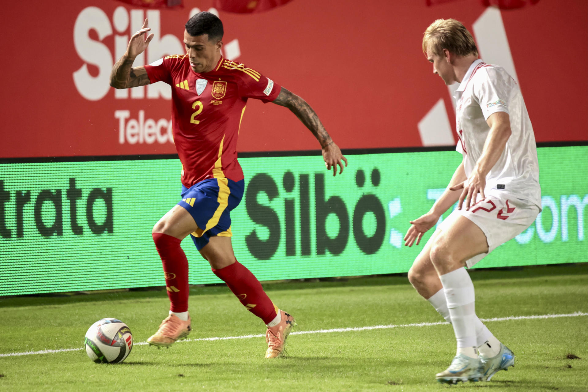El defensa de la selección española, Pedro Porro (i), se lleva el balón ante el defensa de Dinamarca, Victor Kristiansen, durante el encuentro correspondiente a la fase de grupos de la Liga de Naciones que disputan hoy sábado España y Murcia en el estadio Enrique Roca de Murcia. EFE / Juan Carlos Caval. 