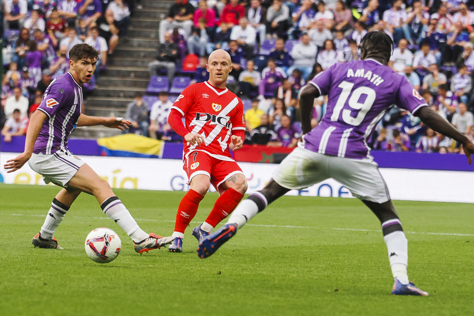 El delantero del Rayo Vallecano Isi Palazón (c) centra el balón entre los jugadores del Valladolid, durante el partido de la novena jornada de LaLiga EA Sports disputado entre el Real Valladolid y el Rayo Vallecano en el estadio José Zorrilla de Valladolid. EFE/R. García 