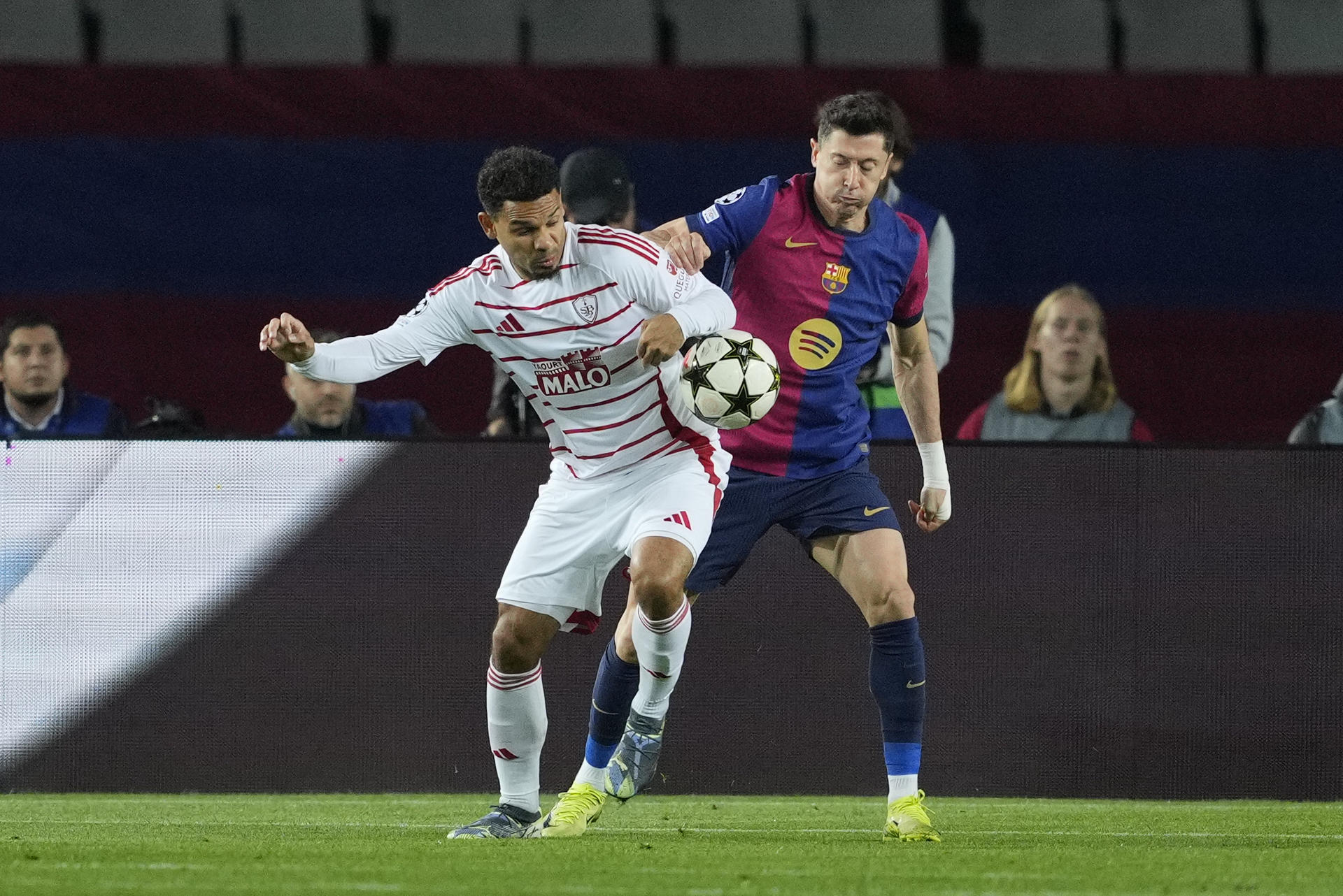 El delantero polaco del FC Barcelona Robert Lewandowski (d) disputa un balón ante el defensa francés del Brest Kenny Lala durante el encuentro correspondiente a la fase regular de la Liga de Campeonesen el estadio Lluis Company, en Barcelona. EFE / Alejandro García 