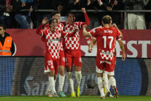 El delantero macedonio del Girona, Bojan Miovski (c), celebra el tercer gol de su equipo durante el encuentro correspondiente a la jornada 14 de Laliga EA Sports en el estadio de Montilivi, en Girona. EFE / Siu Wu.