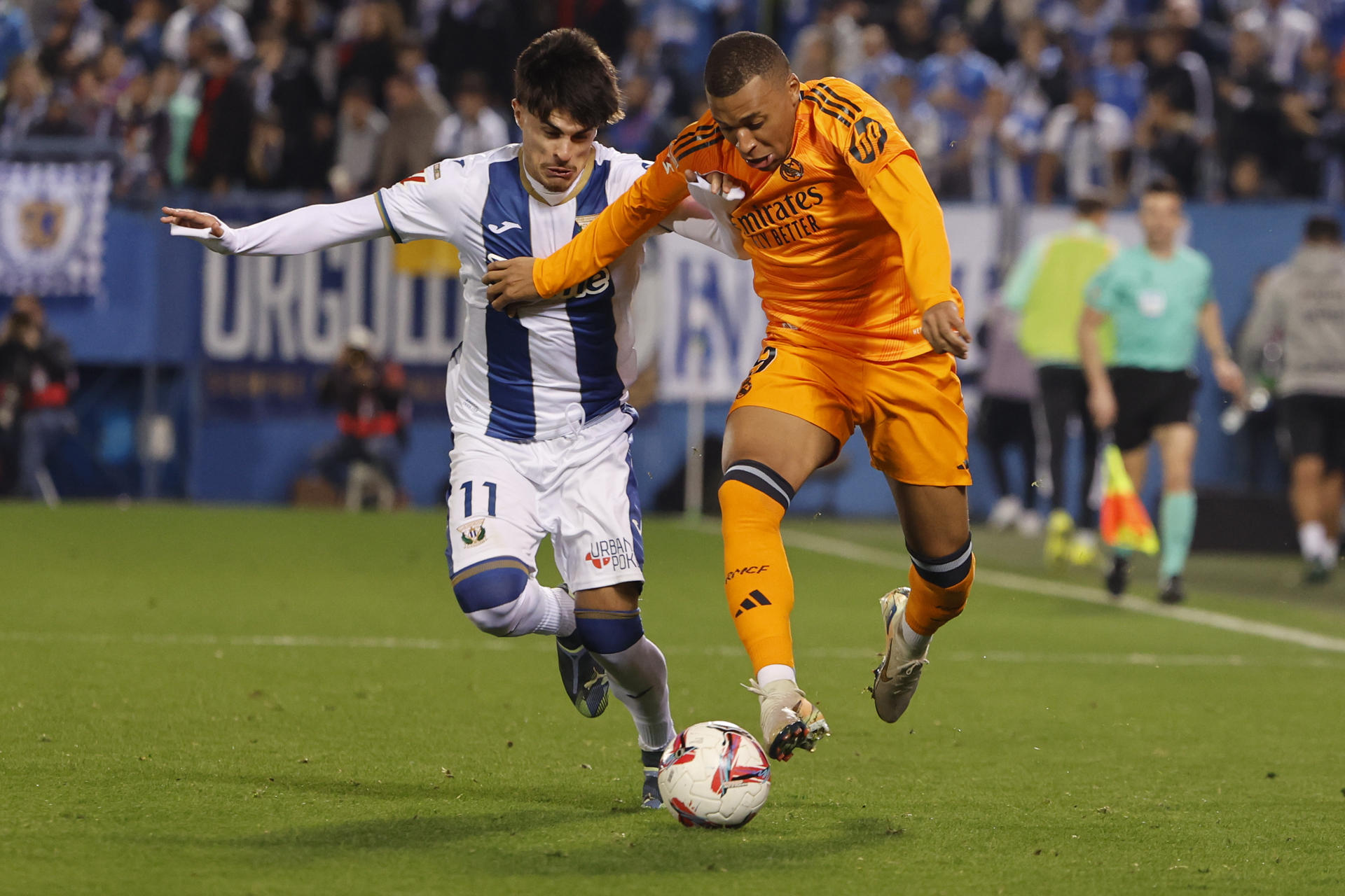 El delantero francés del Real Madrid, Kylian Mbappé (d), disputa el balón ante el delantero del Leganés, Juan Cruz, durante el encuentro correspondiente a la jornada 14 de Laliga EA Sports disputado Leganés y Real Madrid en el estadio de Butarque, en Leganés. EFE / Sergio Pérez.