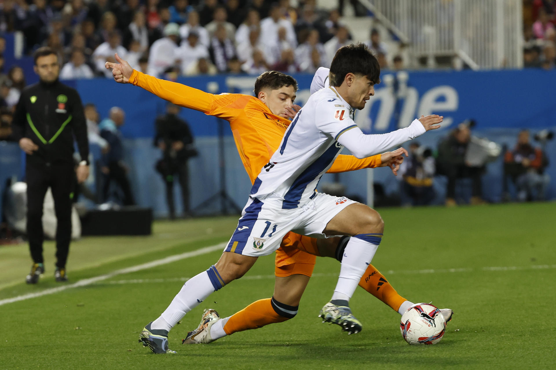 El delantero del Leganés, Juan Cruz (d), intenta llevarse el balón ante el centrocampista uruguayo del Real Madrid, Federico Valverde, durante el encuentro correspondiente a la jornada 14 de Laliga EA Sports disputado Leganés y Real Madrid en el estadio de Butarque, en Leganés. EFE / J.J. Guillen. 