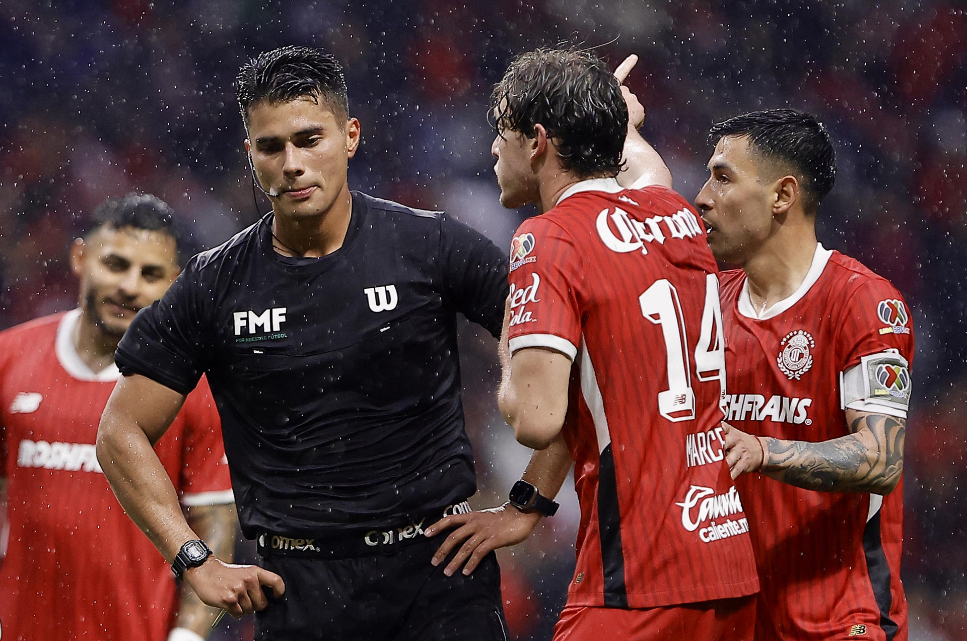 Marcel Ruiz (c) y Claudio Baeza (d) del Toluca reclama al árbitro central Guillermo Pacheco en un partido por la jornada 15 del torneo Apertura 2024 de la Liga MX. EFE/ Alex Cruz 