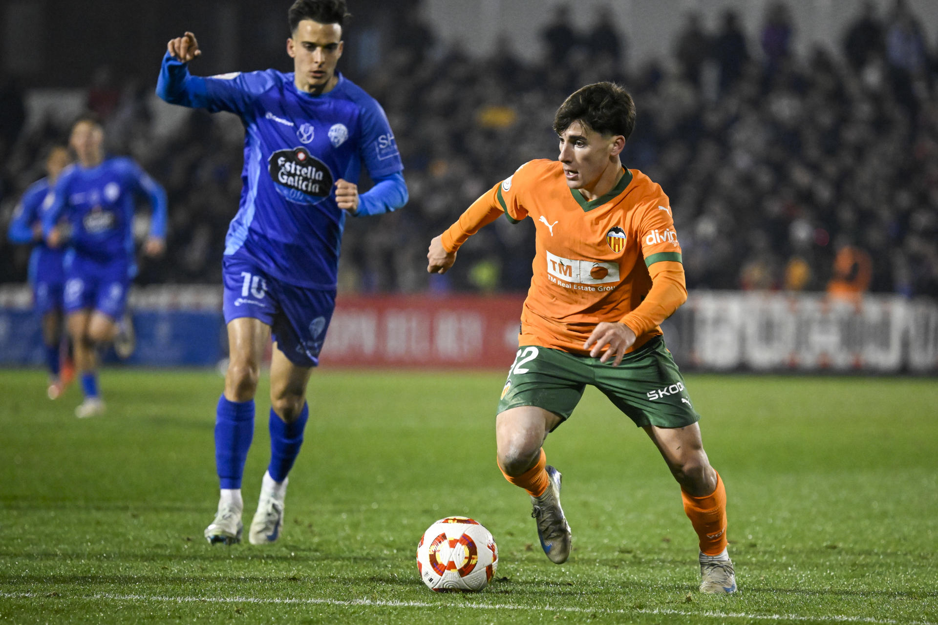 El delantero del Valencia, Martín Tejón (d), conduce el balón ante el jugador del Ourense CF, Alberto Gil, durante el encuentro correspondiente a los octavos de final de la Copa del Rey que disputaron Ourense CF y Valencia en el estadio O Couto, en Ourense. EFE / Brais Lorenzo. 