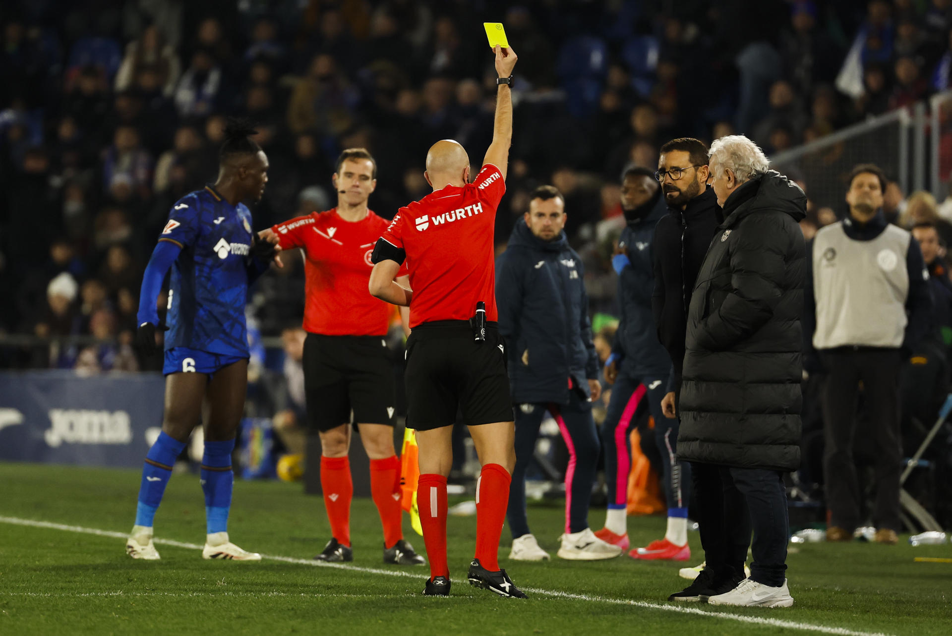 El colegiado González Fuertes muestra tarjeta amarilla al técnico del Getafe, Pepe Bordalás (2d), durante el encuentro correspondiente a la jornada 20 de Laliga EA Sports que disputaron Getafe y FC Barcelona en el Coliseum de Getafe. EFE / Chema Moya. 