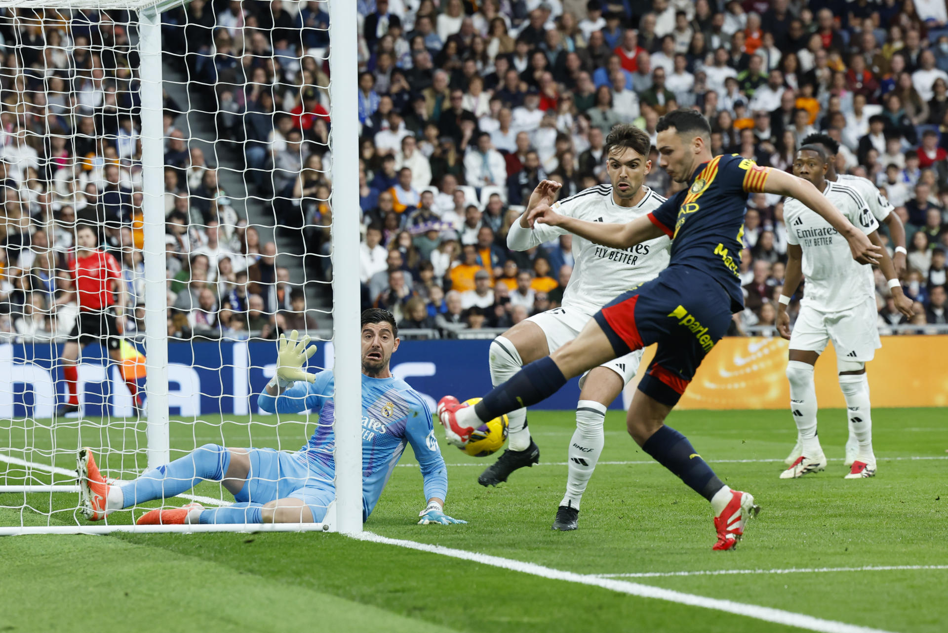 El portero del Real Madrid, el belga Thibaut Courtois (i) intenta detener un ataque del Girona durante el partido de LaLiga entre el Real Madrid y el Girona, este domingo en el estadio Santiago Bernabéu. EFE/ Kiko Huesca 