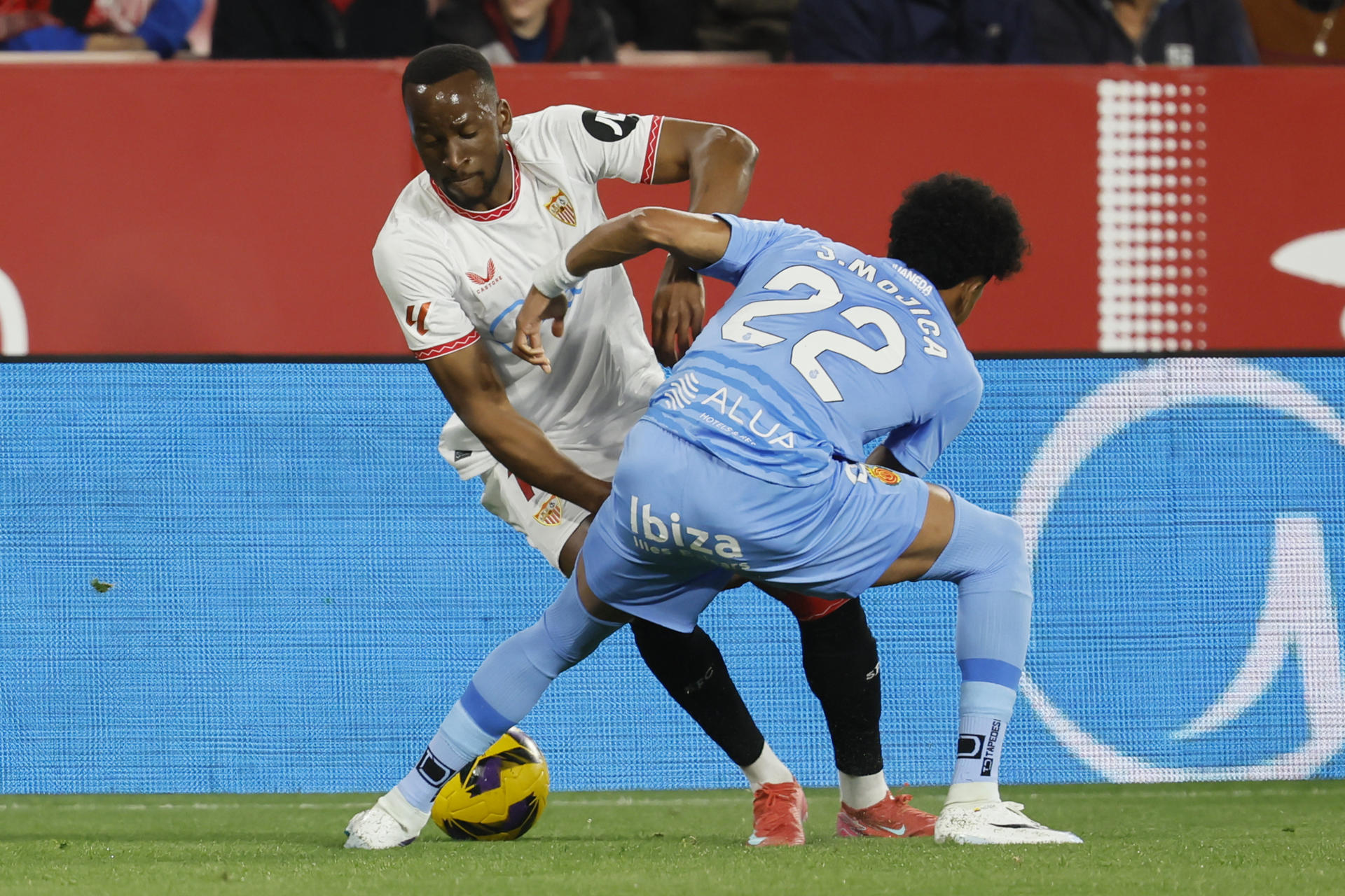 El delantero del Sevilla Dodi Lukébakio (i) trata de escapar de Johan Mojica, del Mallorca, durante el partido de LaLiga de fútbol que Sevilla FC y RCD Mallorca disputan en el estadio Ramón Sánchez-Pizjuán. EFE/José Manuel Vidal