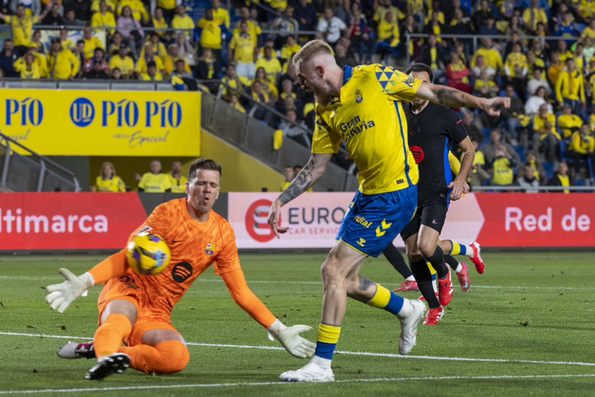 - El guardameta polaco del FC Barcelona, Wojciech Szczesny (i), intenta detener el remate del delantero escocés de la UD Las Palmas, Oli McBurnie, durante el encuentro correspondiente a la jornada 25 de Laliga EA Sports que disputan en el estadio de Gran Canaria. EFE / Quique Curbelo. 