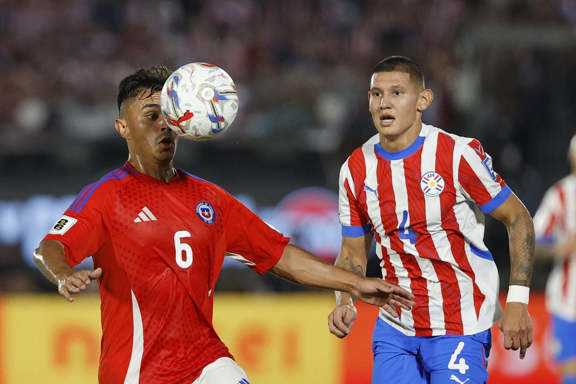 Juan José Cáceres (d) de Paraguay disputa un balón con Vicente Pizarro de Chile en un partido de las eliminatorias sudamericanas para el Mundial de 2026. EFE/ Juan Pablo Pino