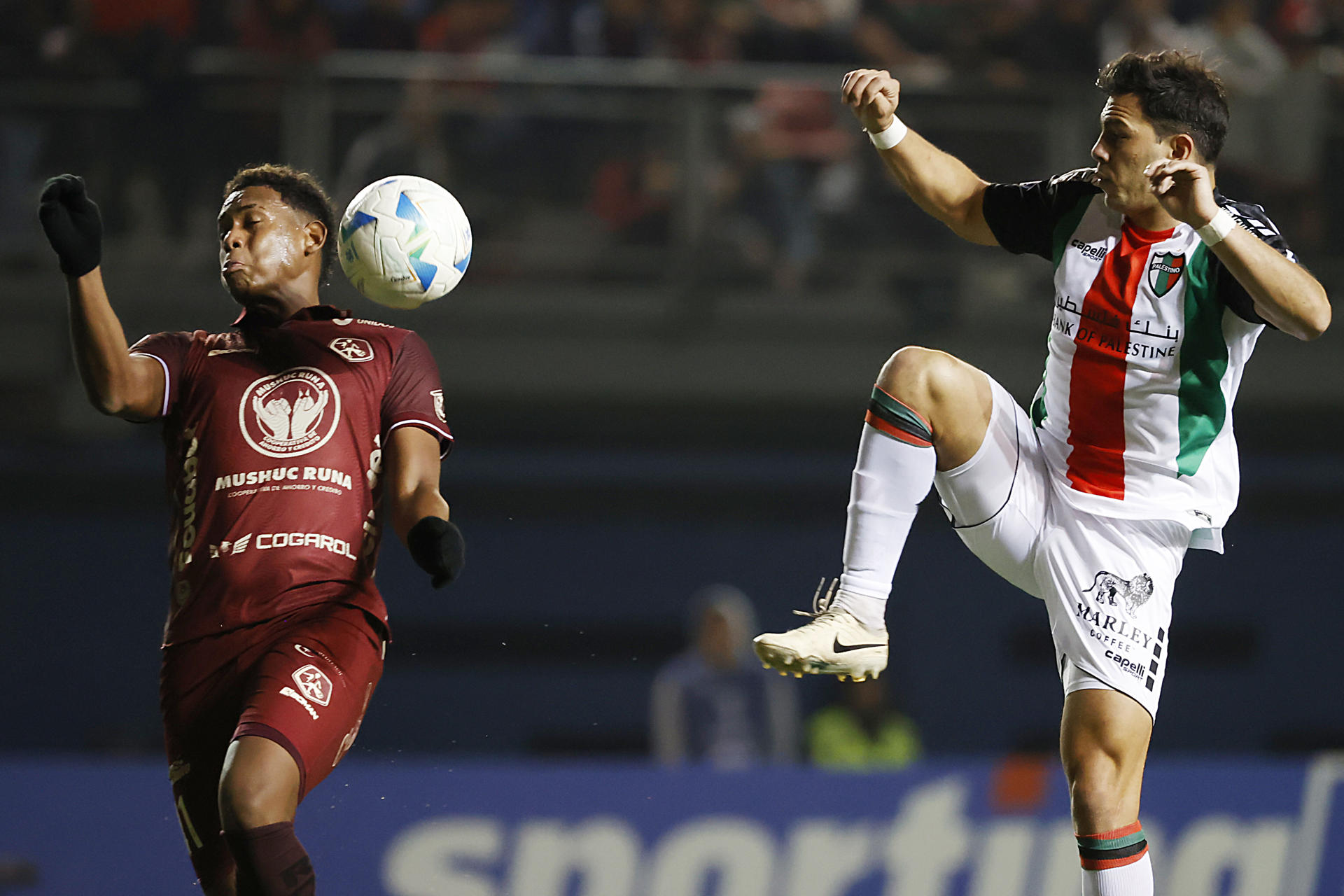 Vicente Espinoza (d) de Palestino disputa el balón con Elián Joshué Caicedo de Mushuc Runa este miércoles, durante el partido de cierre de la fase de grupos de la Copa Sudamericana jugado en el estadio Bicentenario de La Florida en Santiago. EFE/ Elvis González