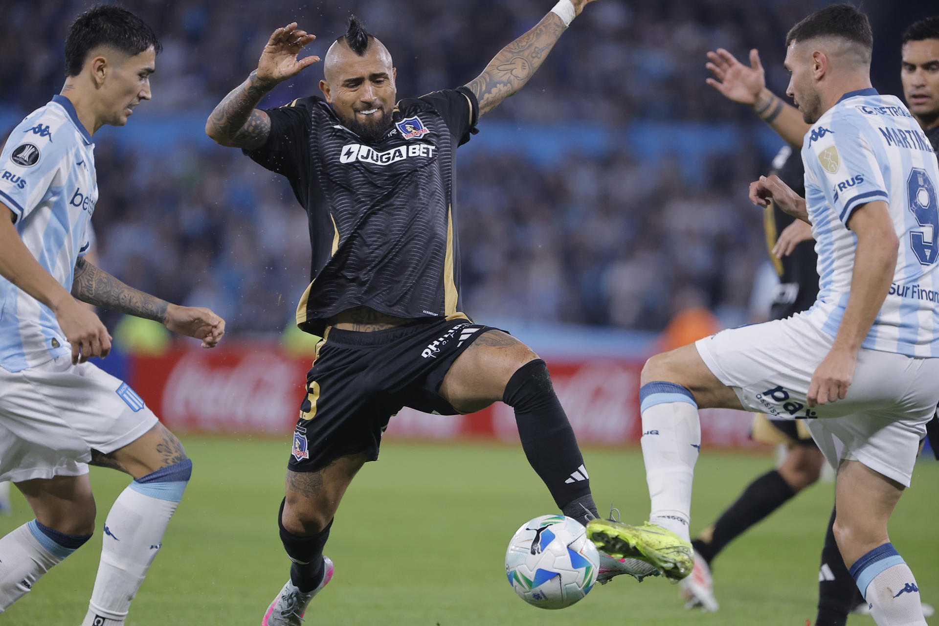 Adrian Martínez, de Racing, disputa un balón con Arturo Vidal (c), de Colo Colo, durante un partido de la fase de grupos de la Copa Libertadores entre Racing y Colo Colo en el estadio Presidente Perón en Avellaneda (Argentina). EFE/ Juan Ignacio Roncoroni