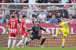 El delantero del Villarreal, Álex Baena (d), remata ante el guardameta argentino del Girona, Paulo Gazzaniga, durante el encuentro correspondiente a la jornada 35 de Laliga EA Sports que disputaron Girona y Villarreal en el estadio municipal de Montilivi, en Girona. EFE/David Borrat.