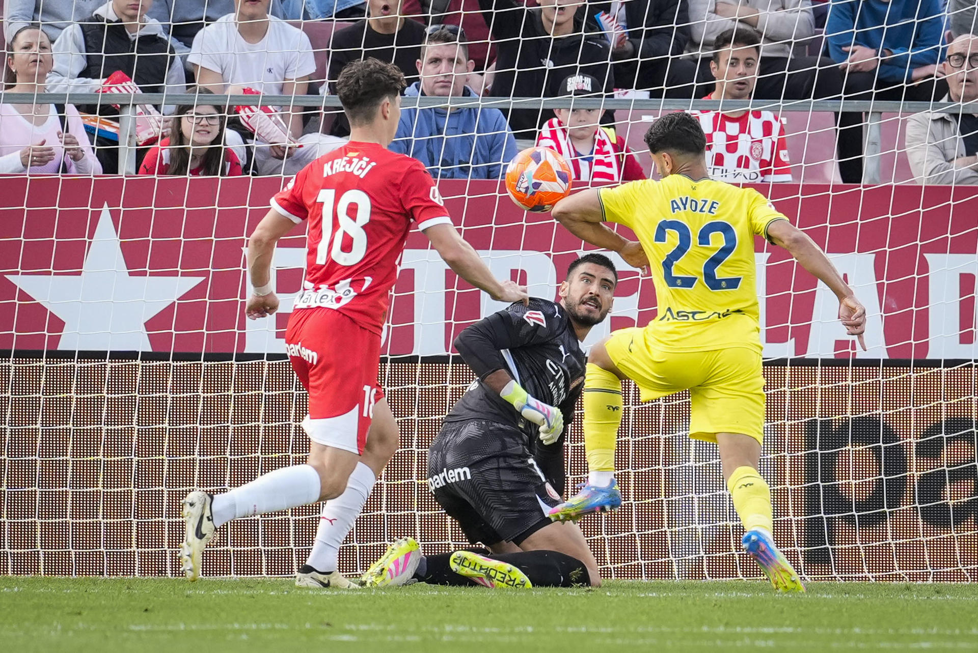 El delantero del Villarreal, Álex Baena (d), remata con el brazo ante el guardameta argentino del Girona, Paulo Gazzaniga, durante el encuentro correspondiente a la jornada 35 de Laliga EA Sports que disputaron Girona y Villarreal en el estadio municipal de Montilivi, en Girona. EFE/David Borrat.