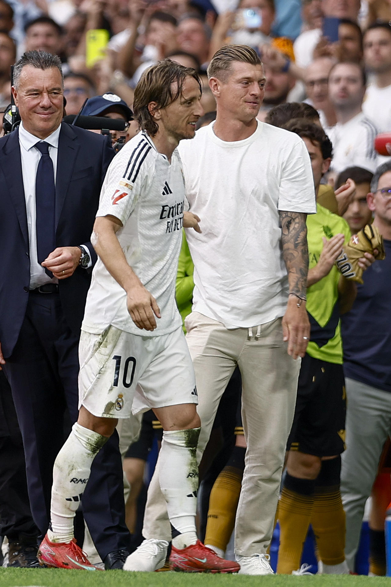 El centrocampista croata del Real Madrid Luka Modrić (c) se abraza con el ex jugador Toni Kroos (d) tras ser sustituido en su último partido en el Santiago Bernabéu durante el partido de la jornada 38 de LaLiga EA Sports entre Real Madrid y Real Sociedad celebrado este sábado en el estadio Santiago Bernabéu de Madrid. EFE/ Daniel González