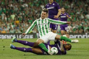 El centrocampista argentino del Betis, Giovani Lo Celso, cae ante el defensor de la Fiorentina durante el partido de ida de las semifinales de la Liga Conferencia en Sevilla. EFE/Julio Muñoz