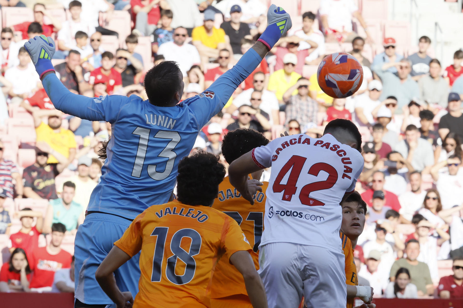 El guardameta del Real Madrid Andriy Lunin (i) despeja un balón en el partido de la jornada 37 de LaLiga que Sevilla FC y Real Madrid disputan este domingo en el estadio Sánchez-Pizjuán, en Sevilla. EFE/José Manuel Vidal