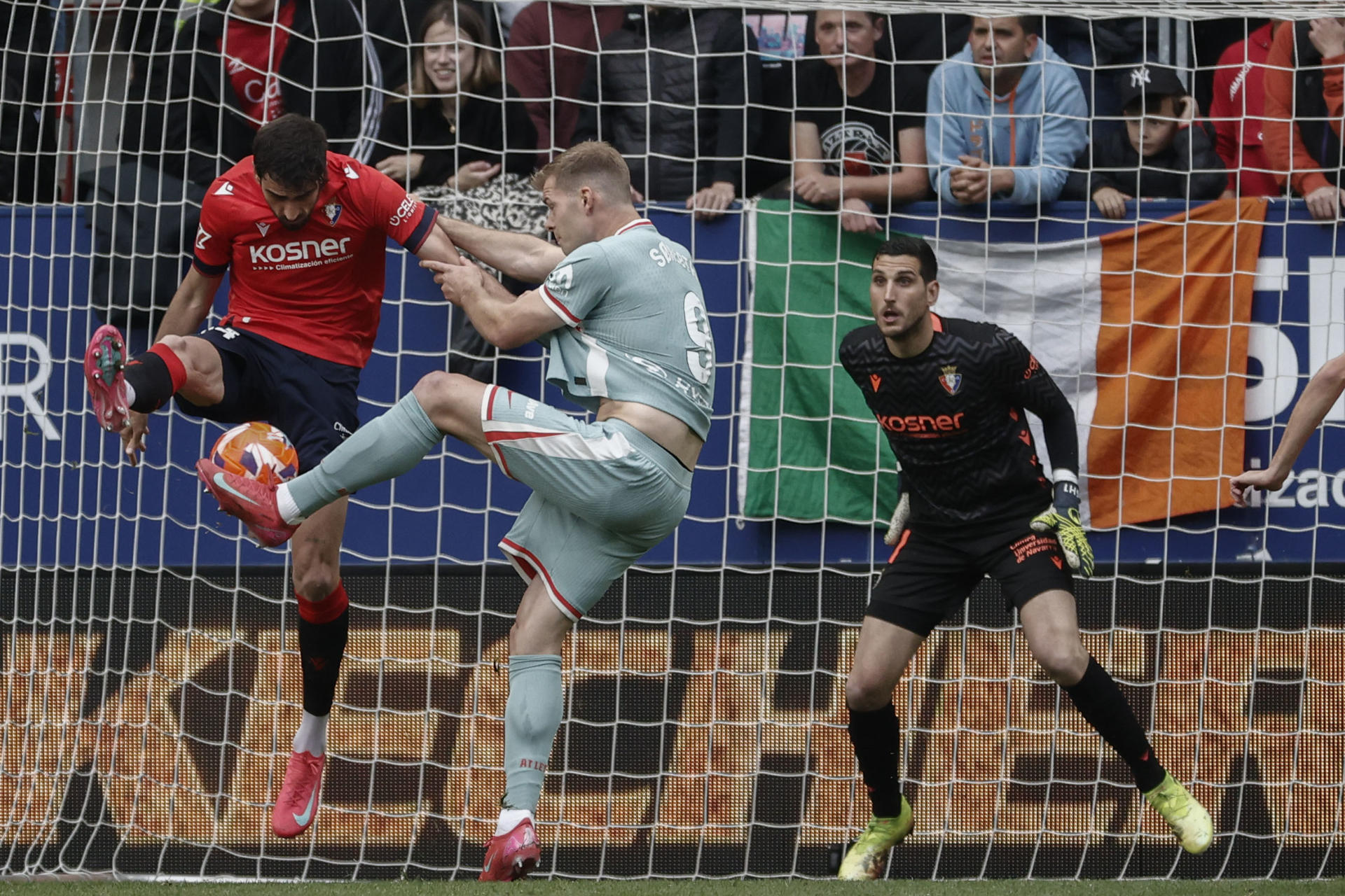 El defensa del Osasuna Alejandro Catena (i) intenta despejar un disparo del delantero noruego del Atlético de Madrid Alexander Sørloth (c) durante el encuentro correspondiente a la jornada 36 de LaLiga EA Sports entre el Osasuna y el Atlético de Madrid este jueves en el Sadar, Pamplona. EFE/ Jesús Diges