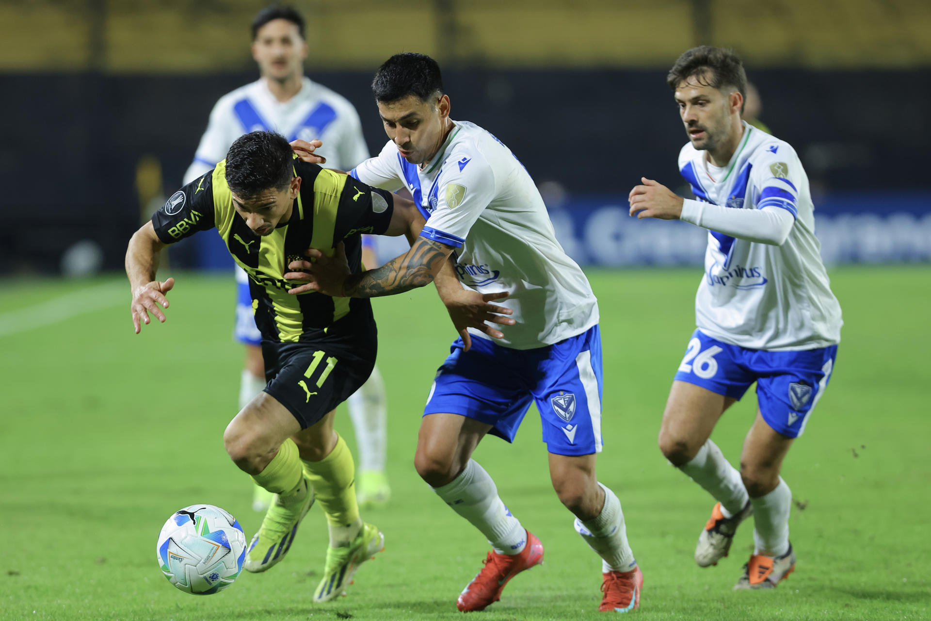 Maximiliano Silvera (i), de Peñarol, disputa un balón con Claudio Baeza (c), de Vélez, en partido de la Copa Libertadores en el estadio Campeón del Siglo en Montevideo. EFE/ Gastón Britos 
